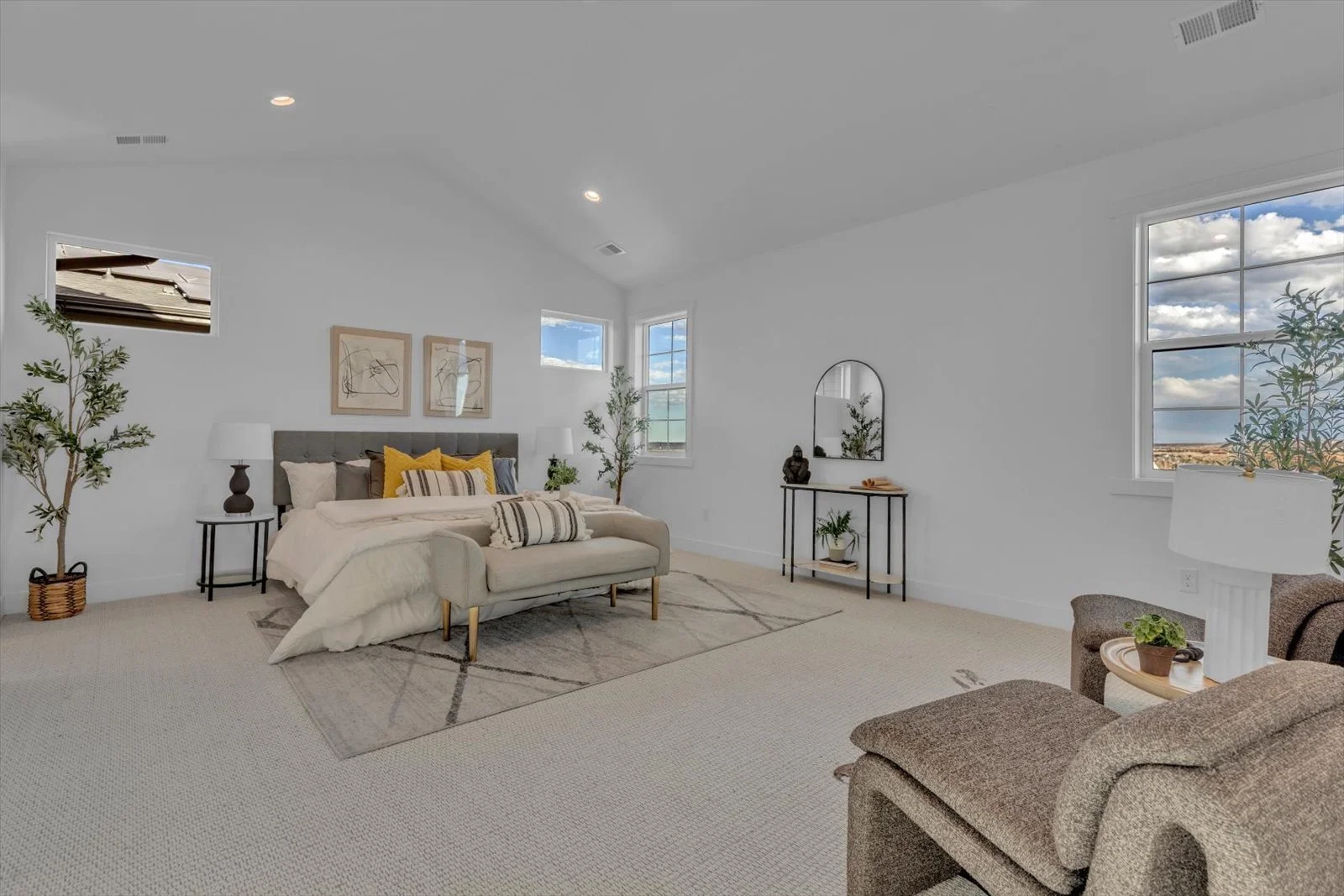 Bedroom with a vaulted ceiling, upholstered bed, and seating beside the windows