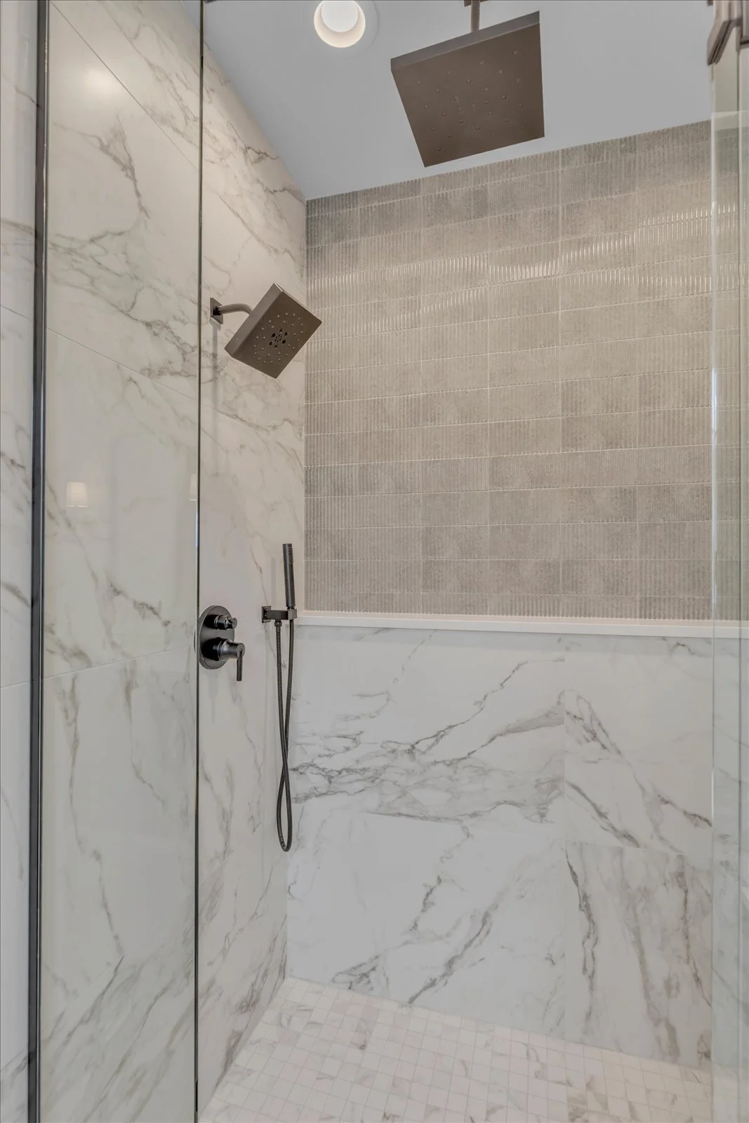 Shower detail with dark square rain heads and contrasting textured tile