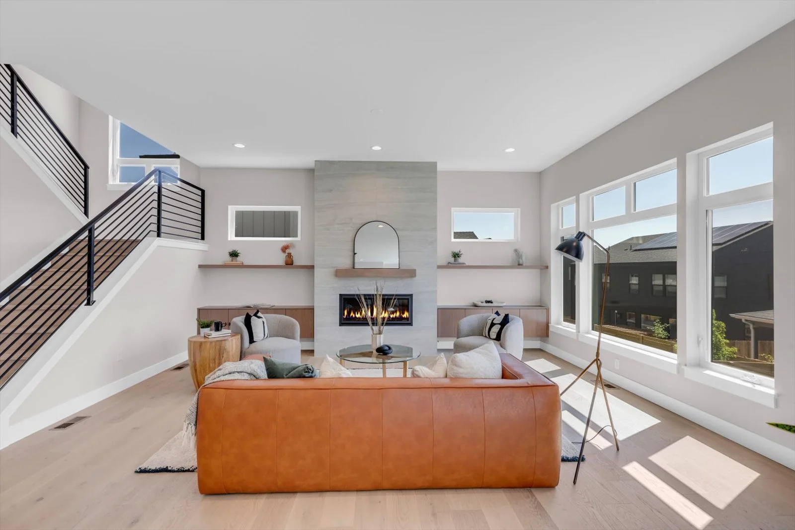 Living room with an orange sofa, linear fireplace, and black stair railing