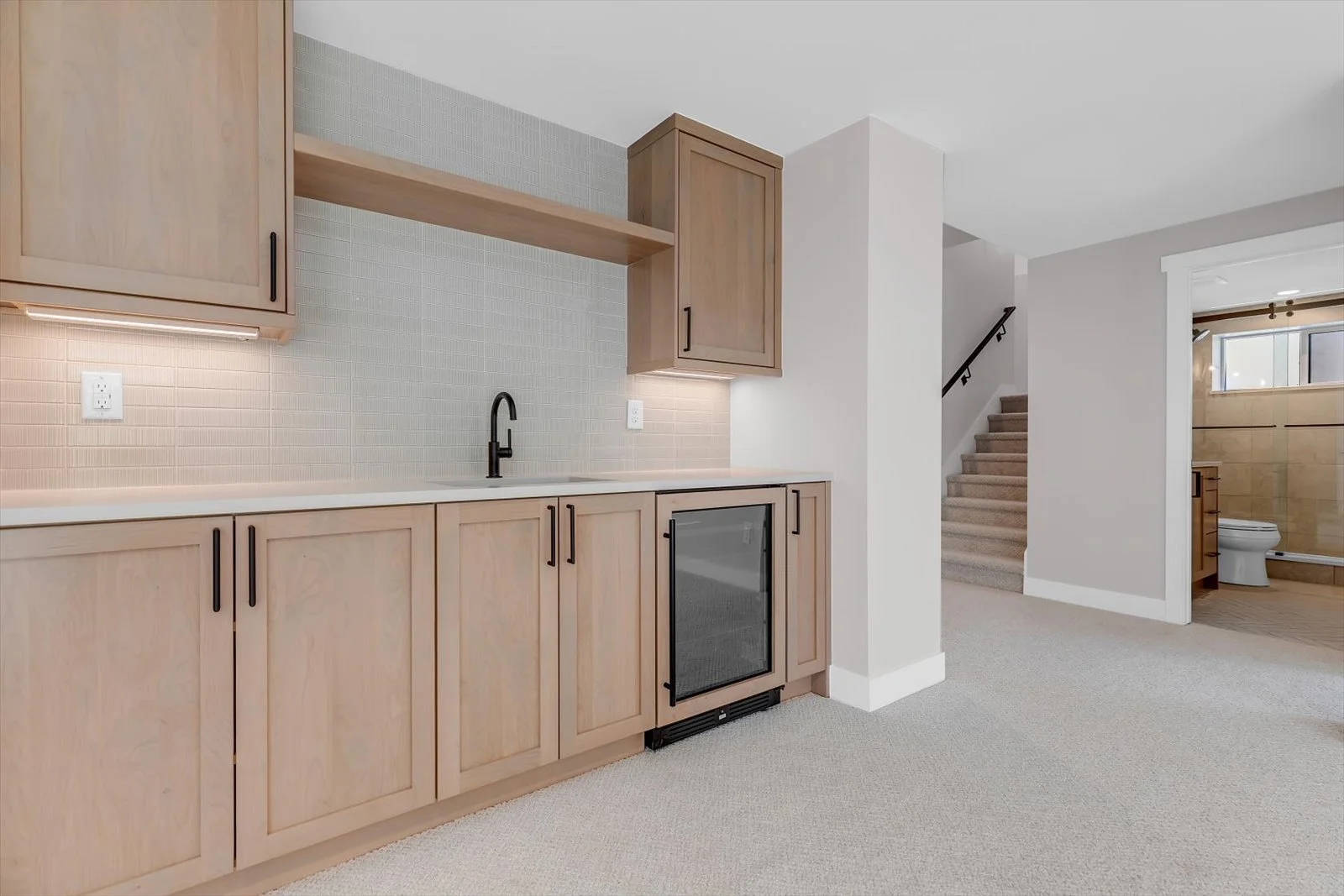 Wood wet-bar cabinetry with a black faucet, open shelf, and glass-front beverage refrigerator