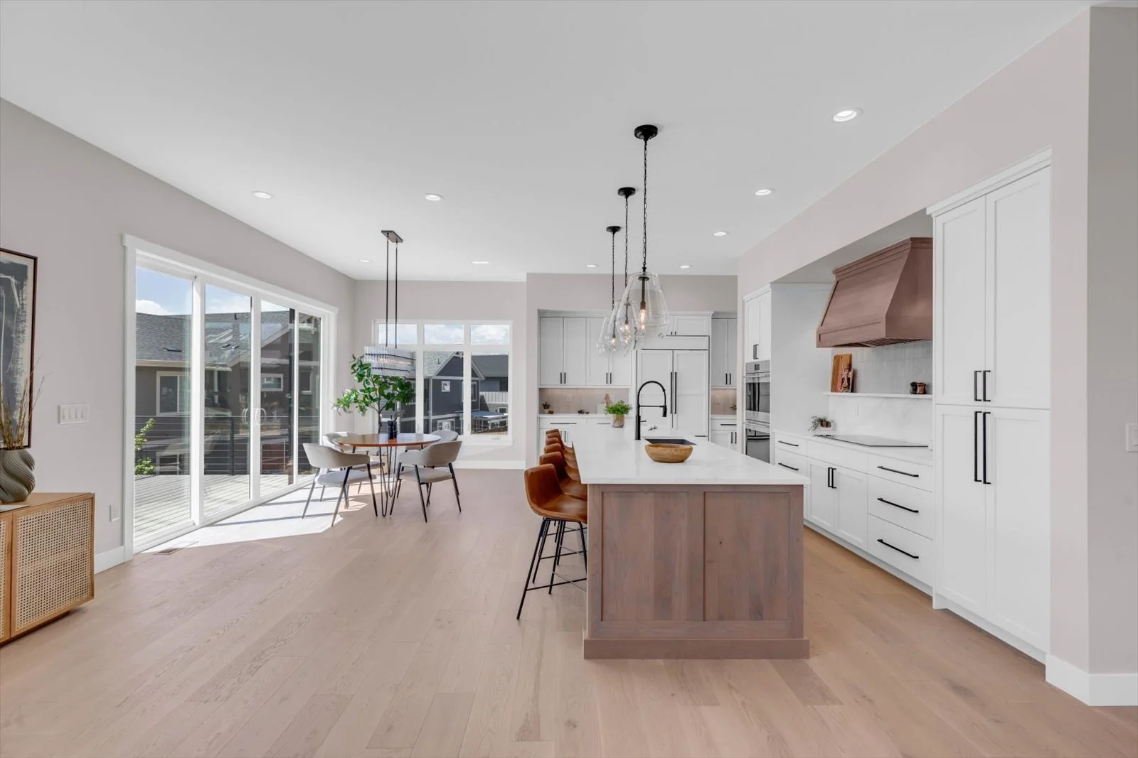 Open kitchen and dining area with a wood island, white cabinets, and glass pendant lights