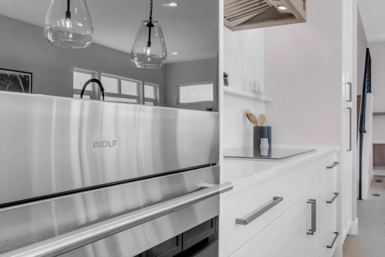 Stainless-steel wall oven beside white kitchen cabinetry and a cooktop