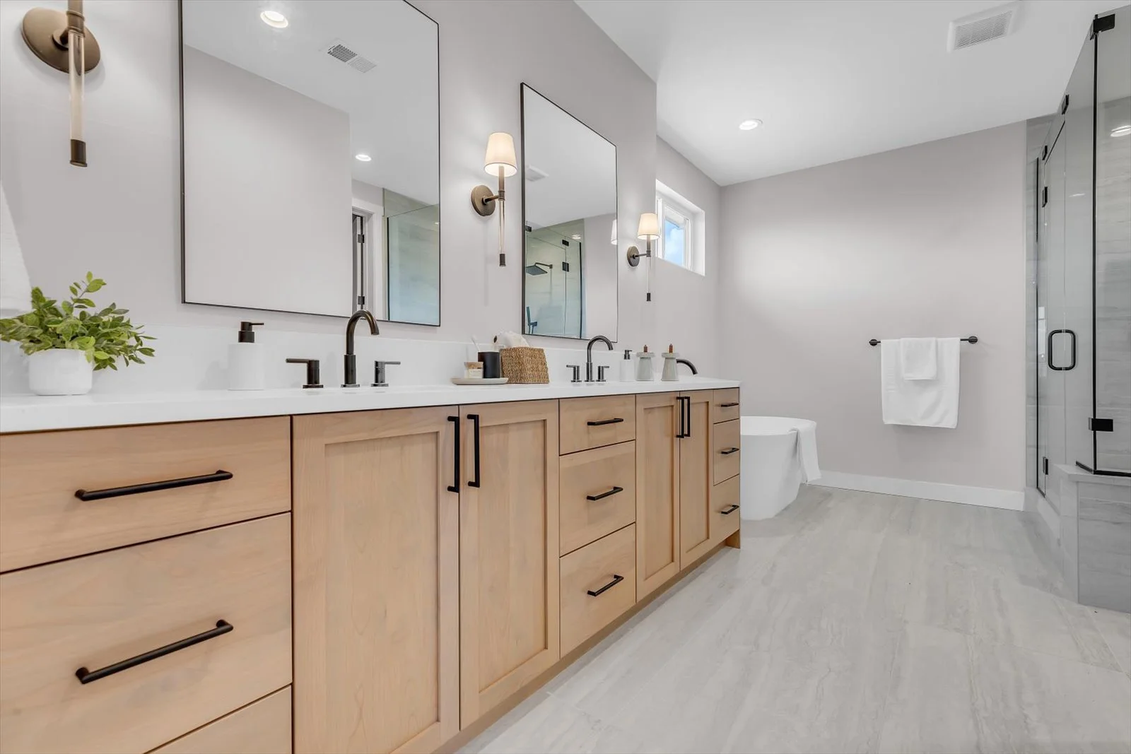 Bathroom with a wood double vanity, black fixtures, and a glass shower