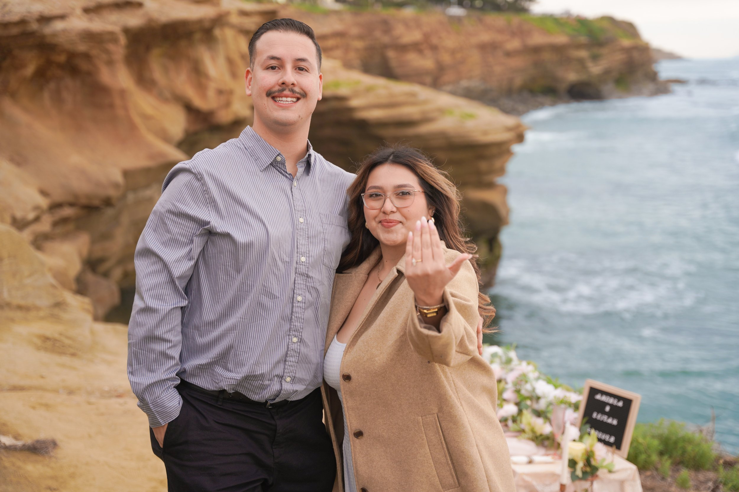 Surprise engagement proposal at Sunset Cliffs San Diego featuring an elevated boho picnic and coastal sunset scenery