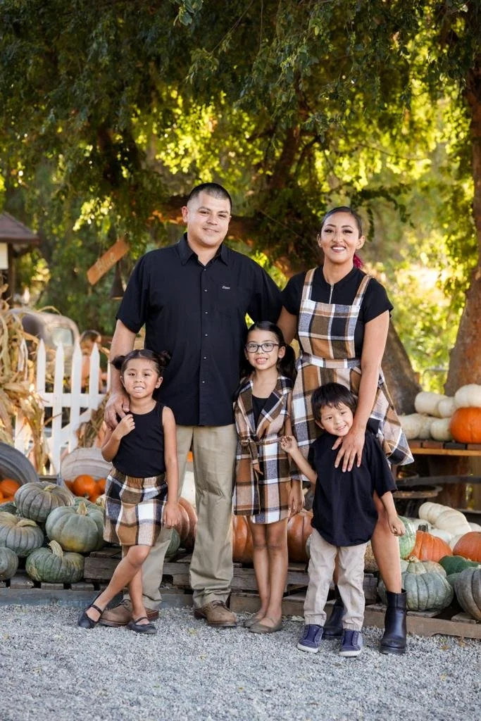 Family group photo framed by hay bales and festive fall décor.