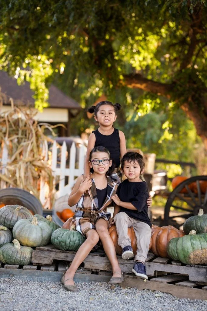 Family fall photography session surrounded by pumpkins and rustic charm.