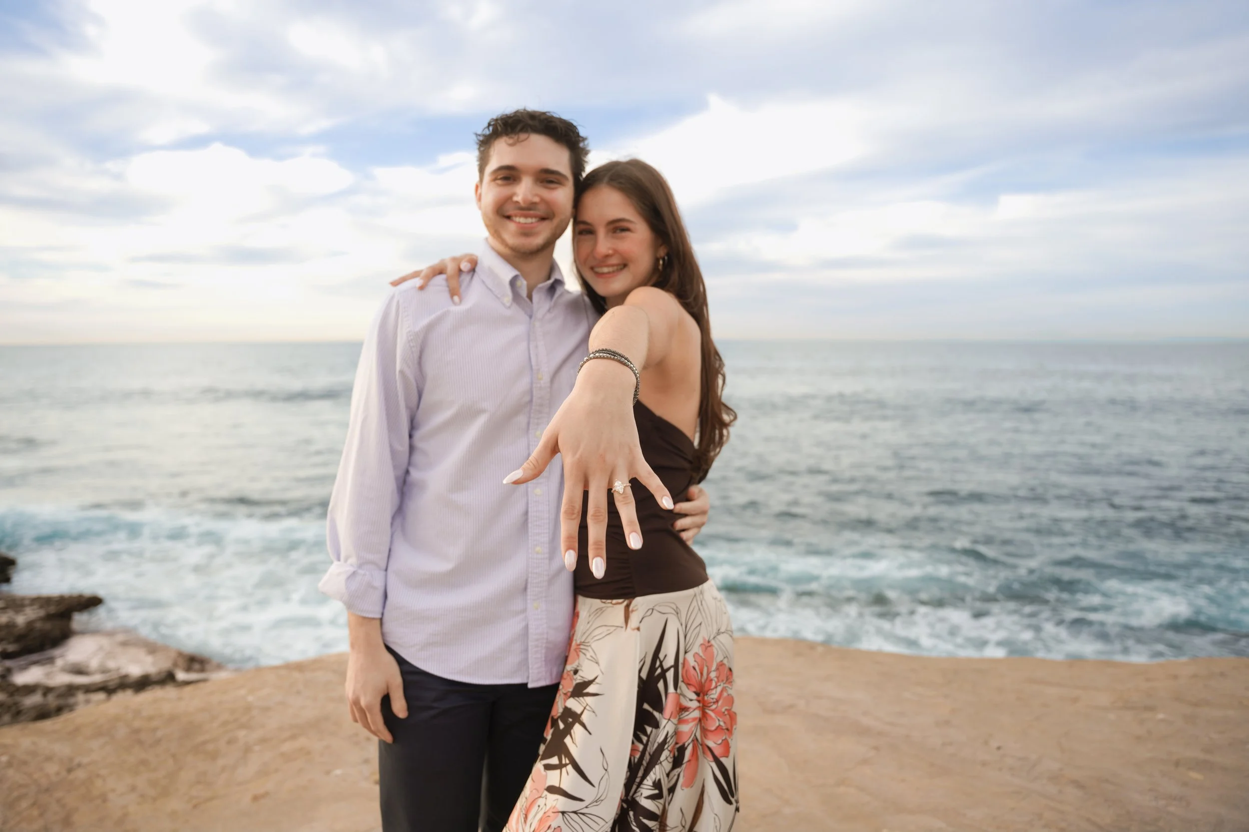 Surprise proposal at La Jolla Cove captured by professional photographer with ocean cliffs, natural light, and candid emotional moment