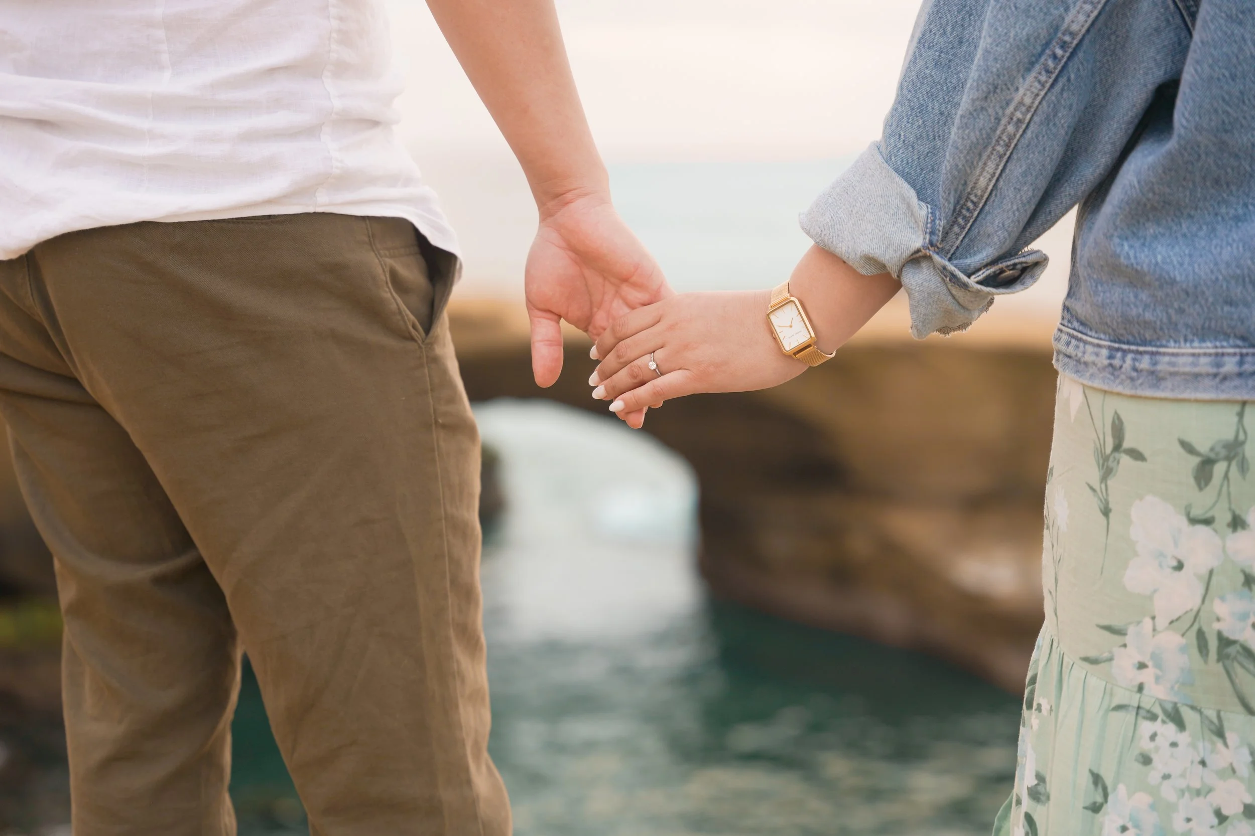 Couple holding hands during a sunset surprise proposal photoshoot overlooking the Pacific Ocean in San Diego, captured by a San Diego surprise proposal photographer for out-of-state clients who booked the Last Minute Yes proposal package