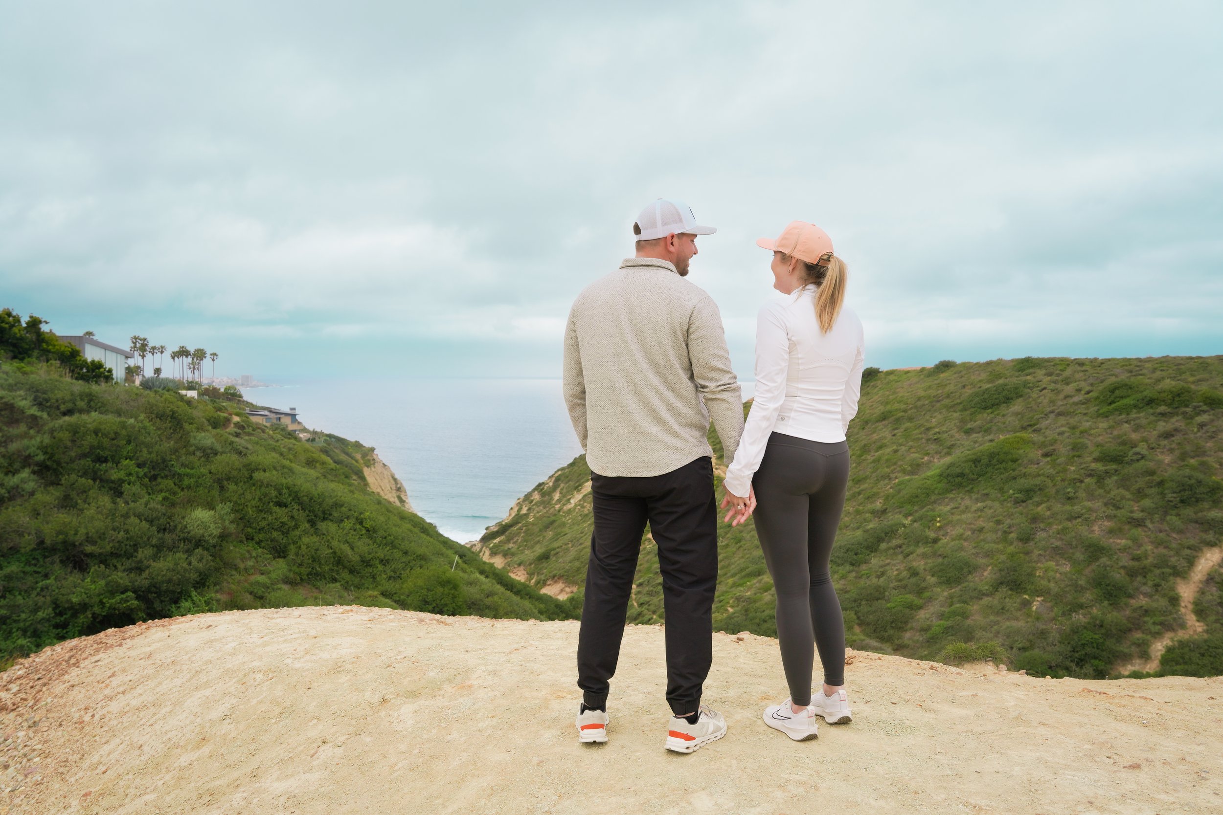 Surprise proposal captured on the Saigon Trail hike in La Jolla, with stunning views of the Pacific Ocean. Book our Undercover Yes Proposal Package for an unforgettable, discreetly captured moment.