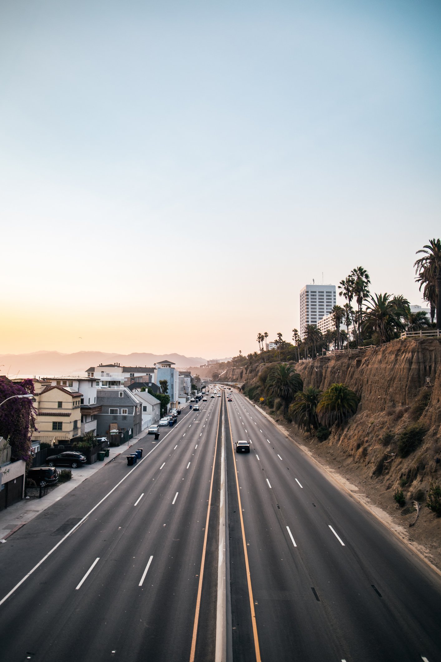 Scenic view driving north on Highway 1, passing Santa Monica and entering Malibu—coastal cliffs, palm trees, and ocean views lining the iconic Pacific Coast Highway. Book your Malibu coastal photoshoot or milestone session today.
