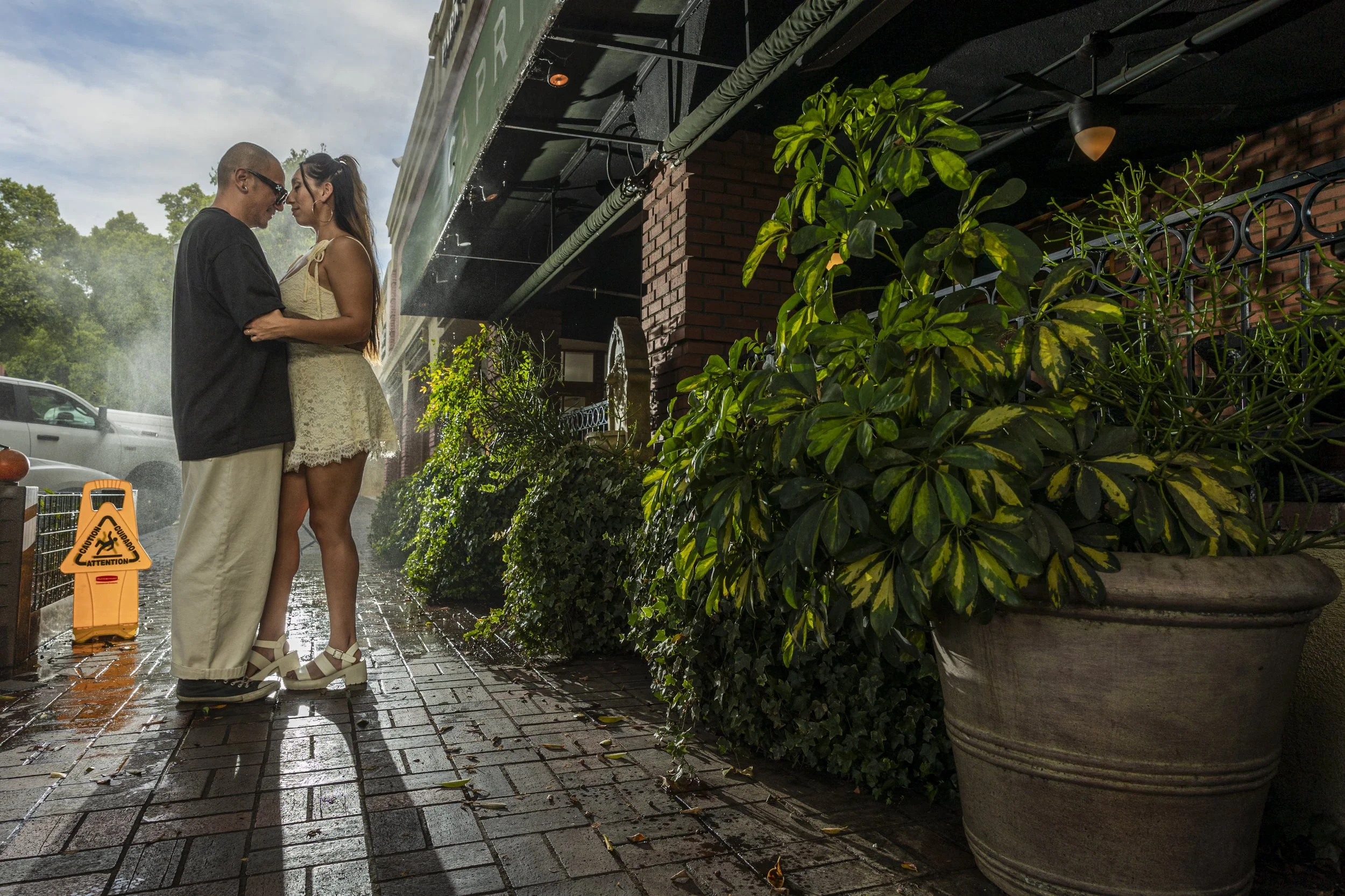  Lifestyle engagement-style photo of couple laughing together against Redlands architecture, showcasing natural emotions and candid photography.    