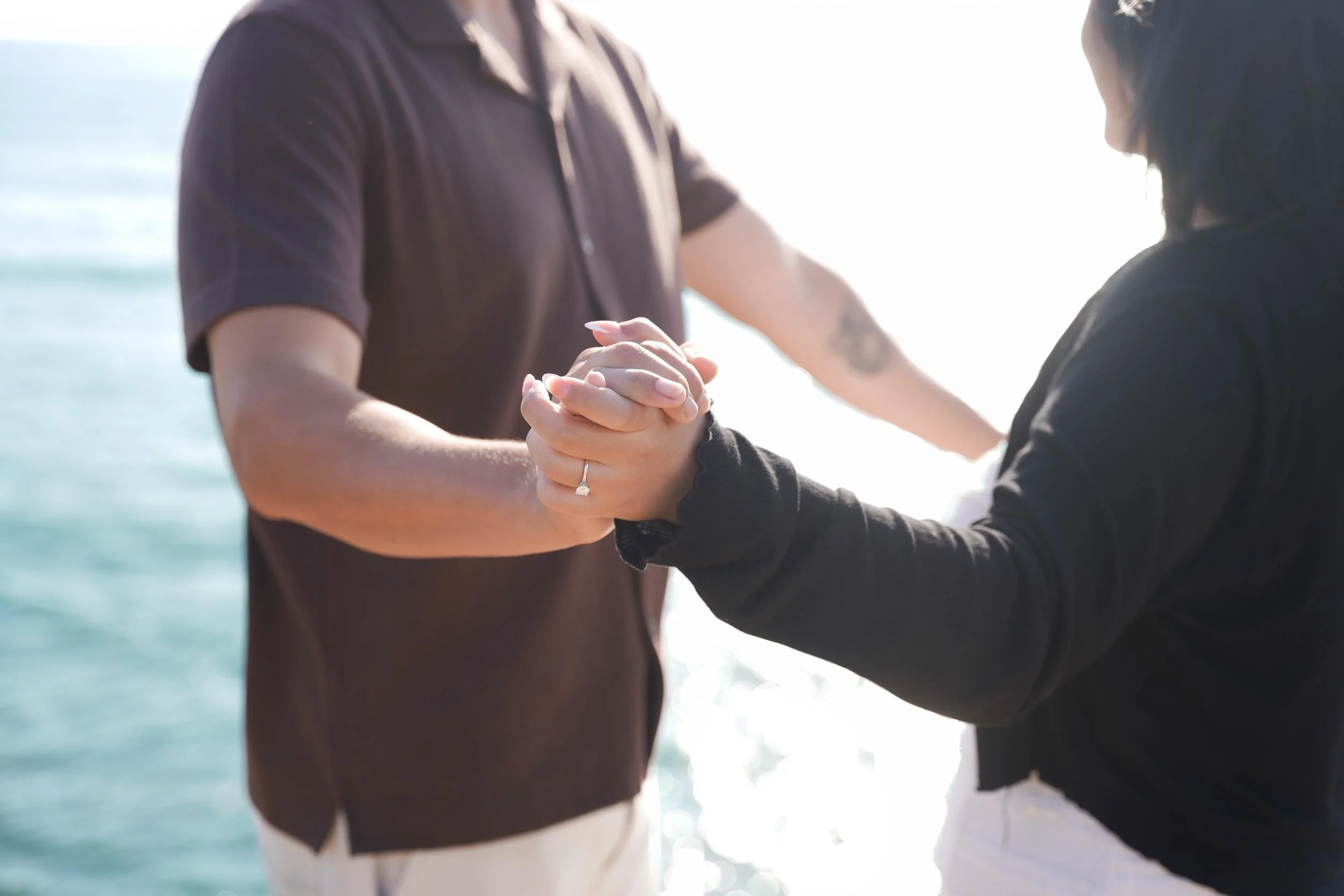 Close-up Sunset Cliffs proposal photography in San Diego capturing the couple dancing and celebrating their love at golden hour.