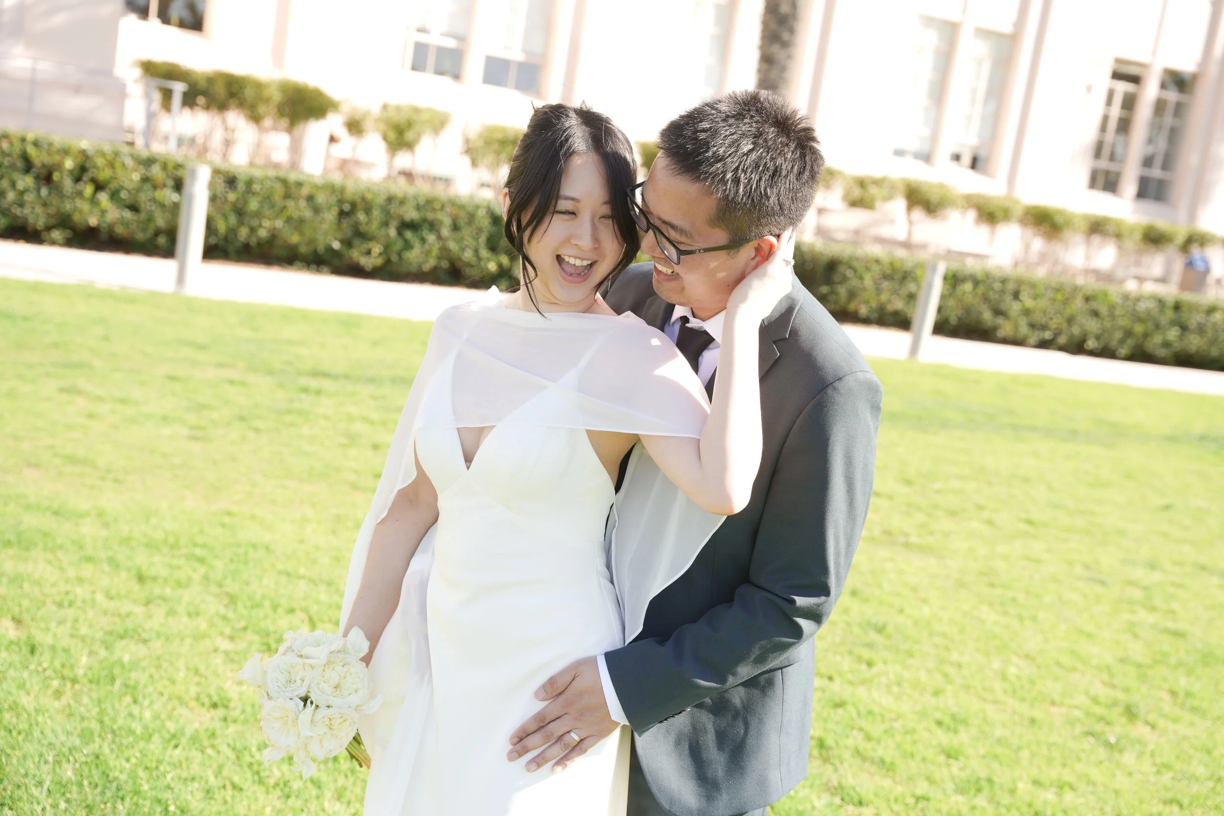 Newly Married Couple Embracing on Waterfront Lawn San Diego