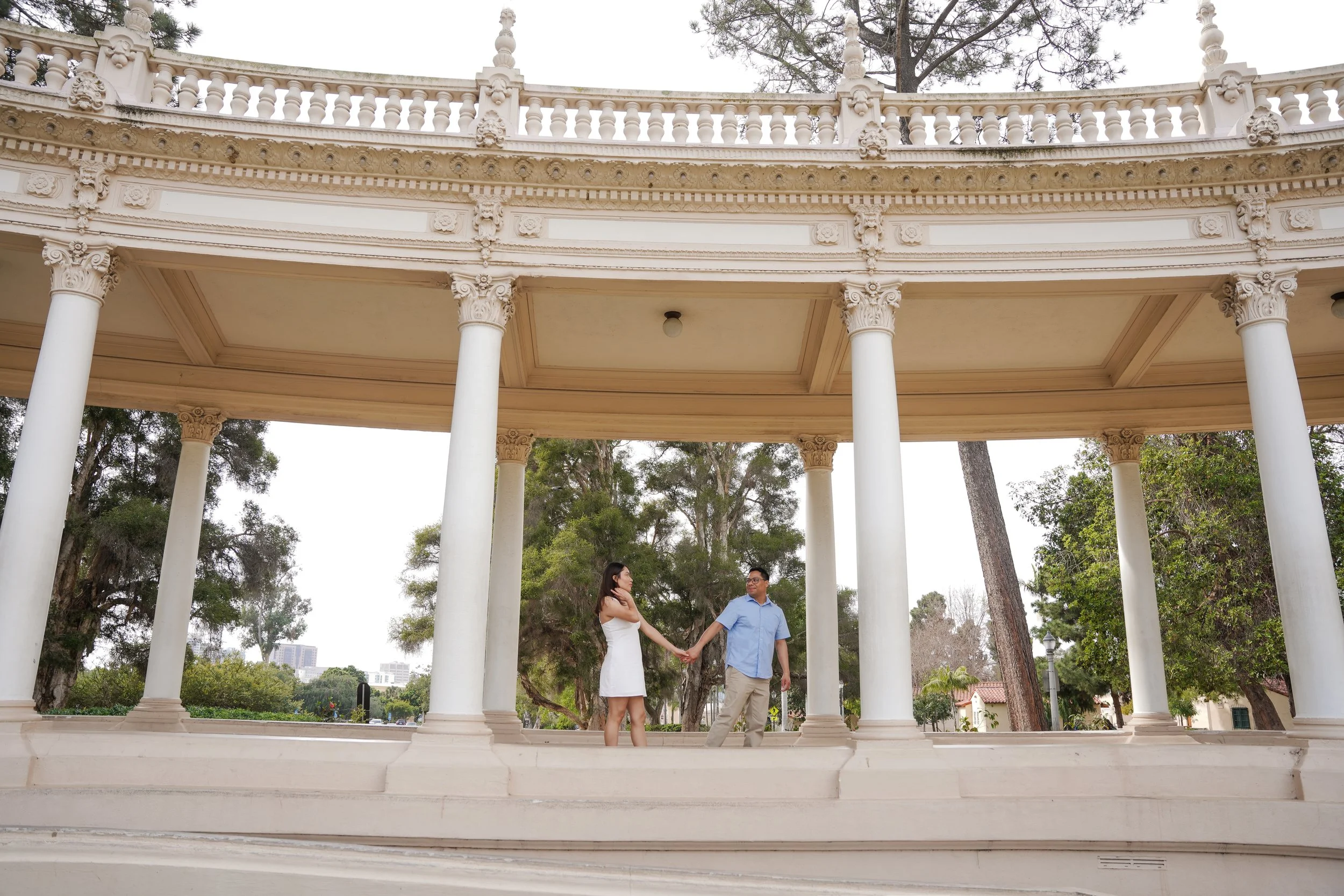 Engaged couple celebrating their proposal at the historic Pavilion in Balboa Park during a surprise proposal photoshoot in San Diego