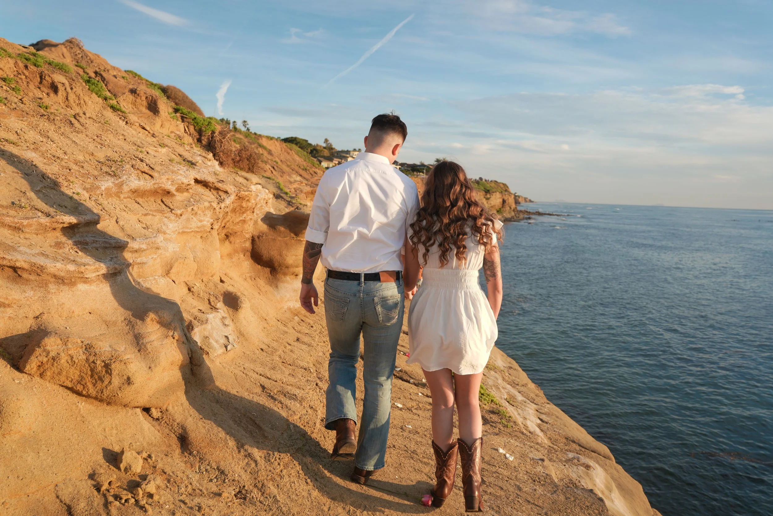 Couple Walking Toward Romantic Sunset Cliffs Picnic Proposal Setup in San Diego