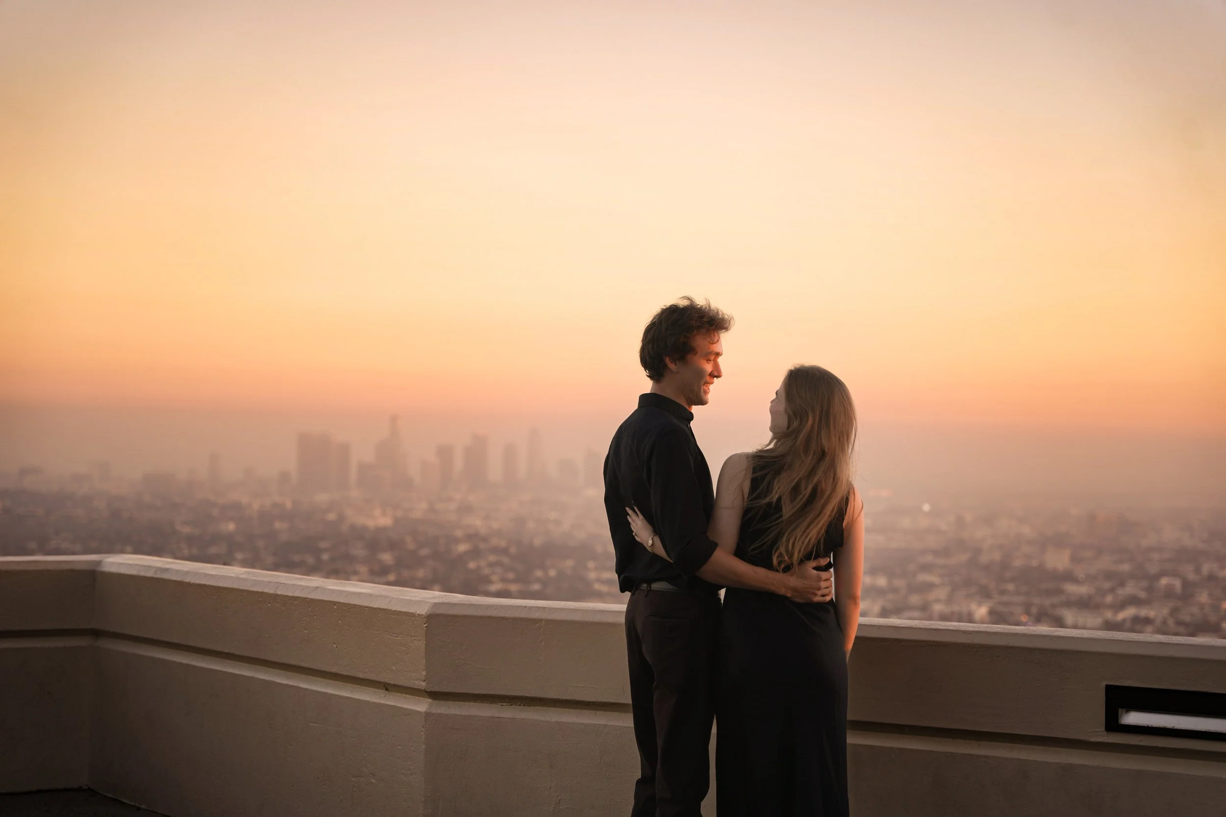 Couple enjoying sunset after surprise proposal on Griffith Observatory deck overlooking Los Angeles skyline Last Minute Yes package