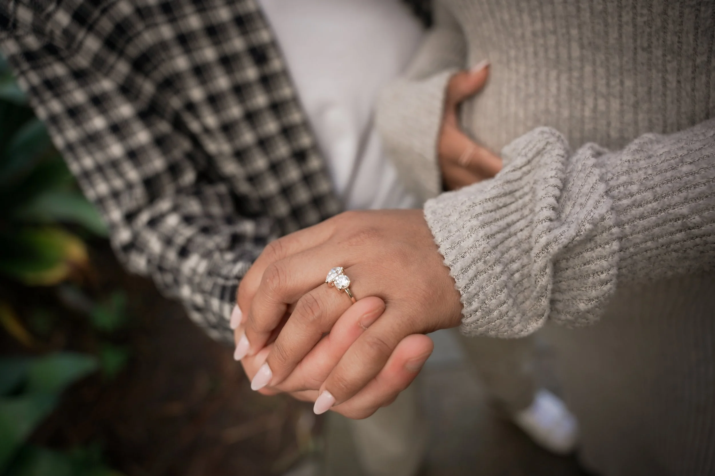 Newly engaged couple strolling hand-in-hand past the Wishing Tree at Estancia La Jolla, showcasing the romantic pathways and lush garden setting.