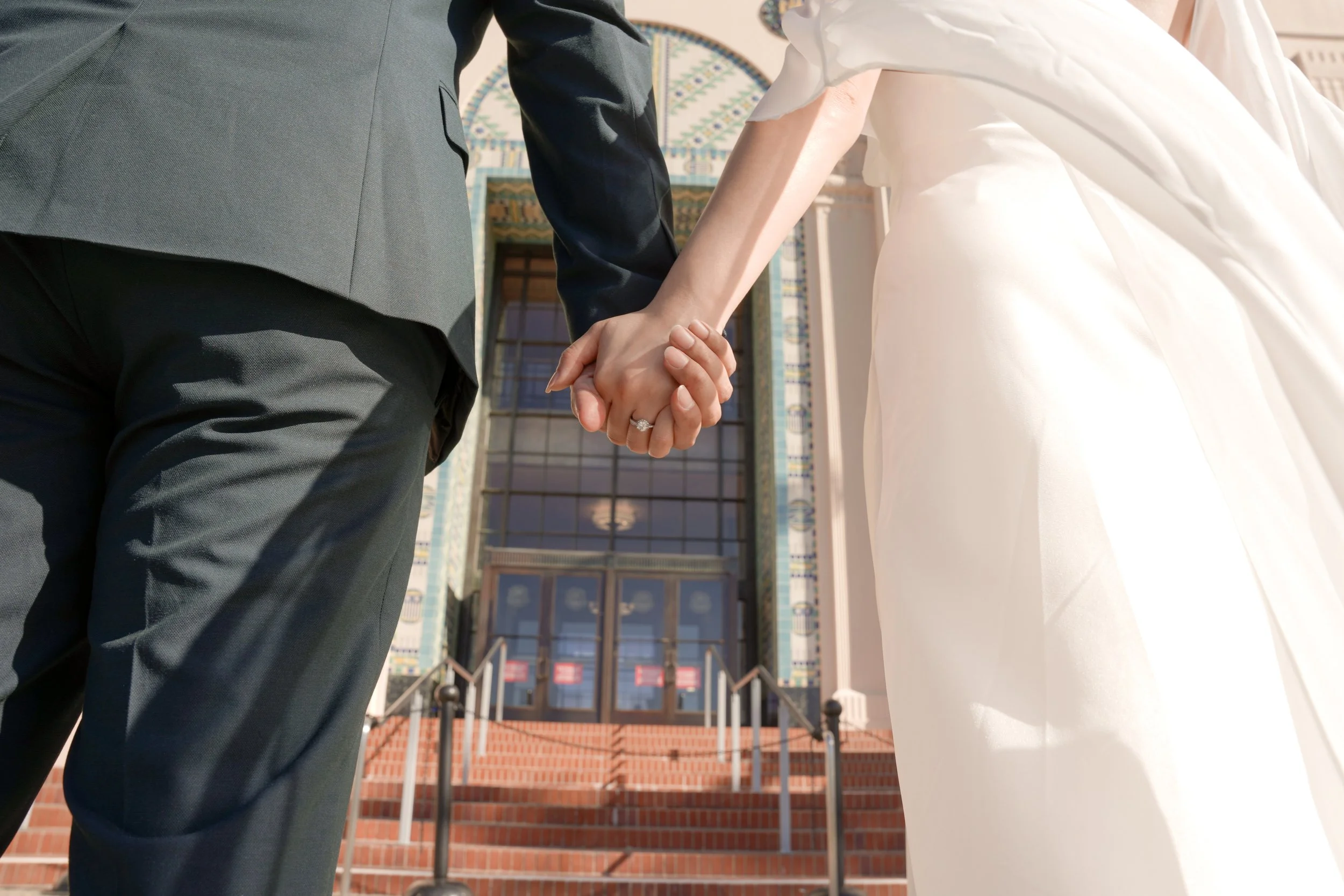 Couple holding hands outside the San Diego County Administration Center moments before entering for their courthouse marriage ceremony, capturing anticipation, connection, and the start of their civil wedding day in downtown San Diego.
