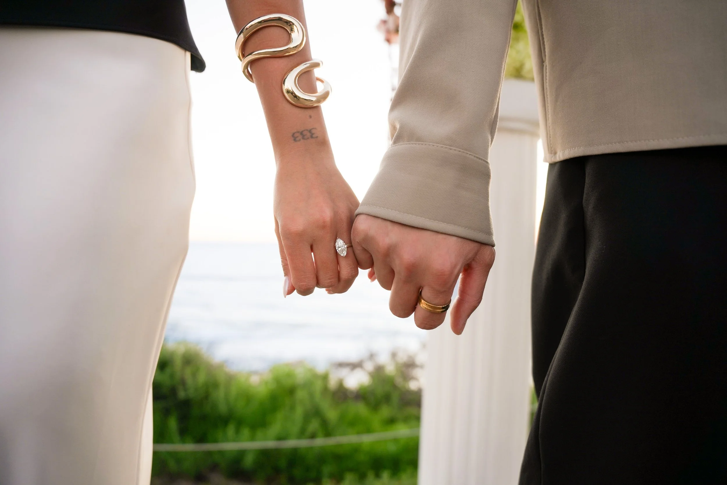 Surprise proposal at Crystal Cove State Beach overlooking the Pacific Ocean as the groom kneels with Newport Beach coastline cliffs in the background