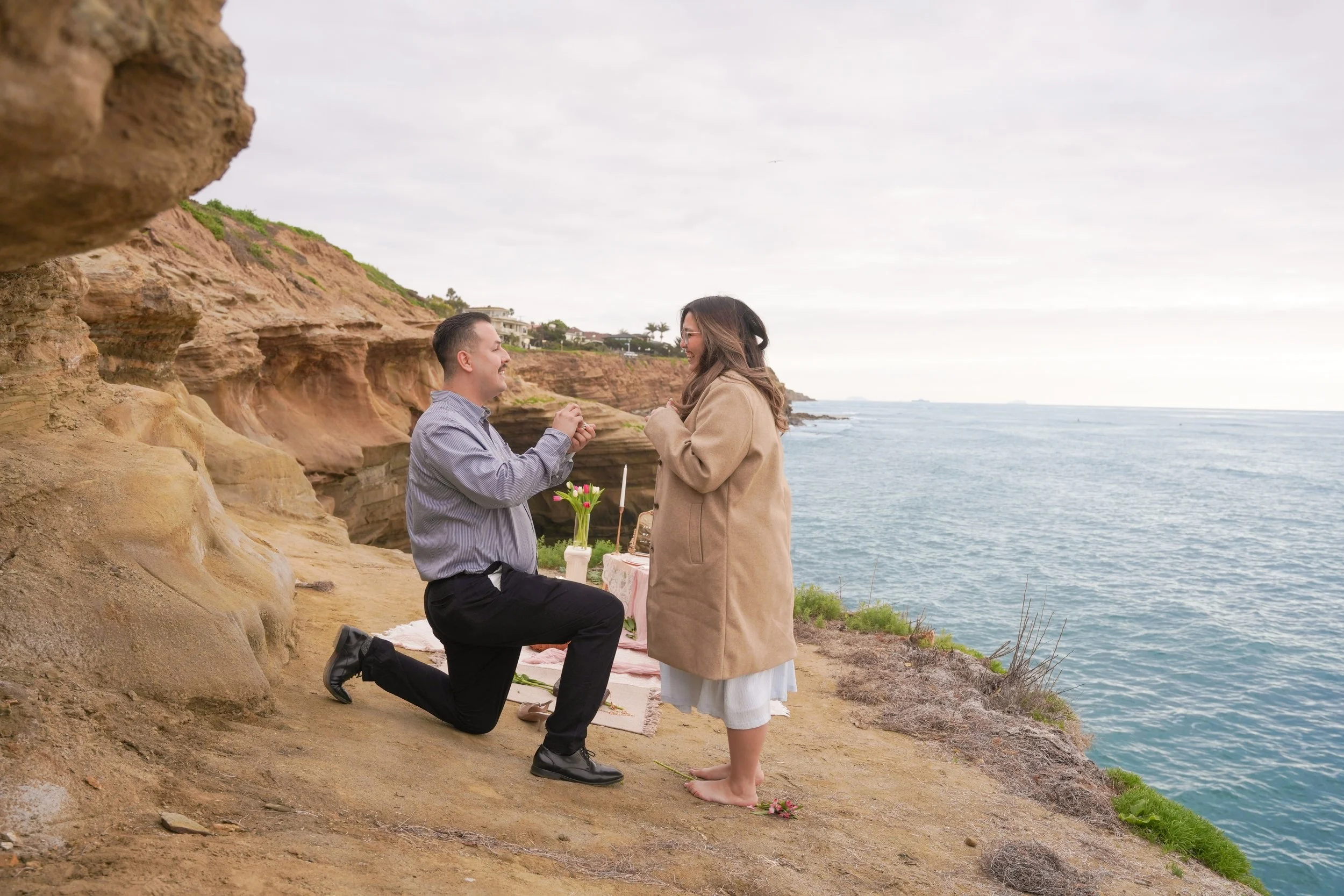 Sunset Cliffs San Diego proposal picnic setup featuring boho styling, candles, florals, and panoramic Pacific Ocean views