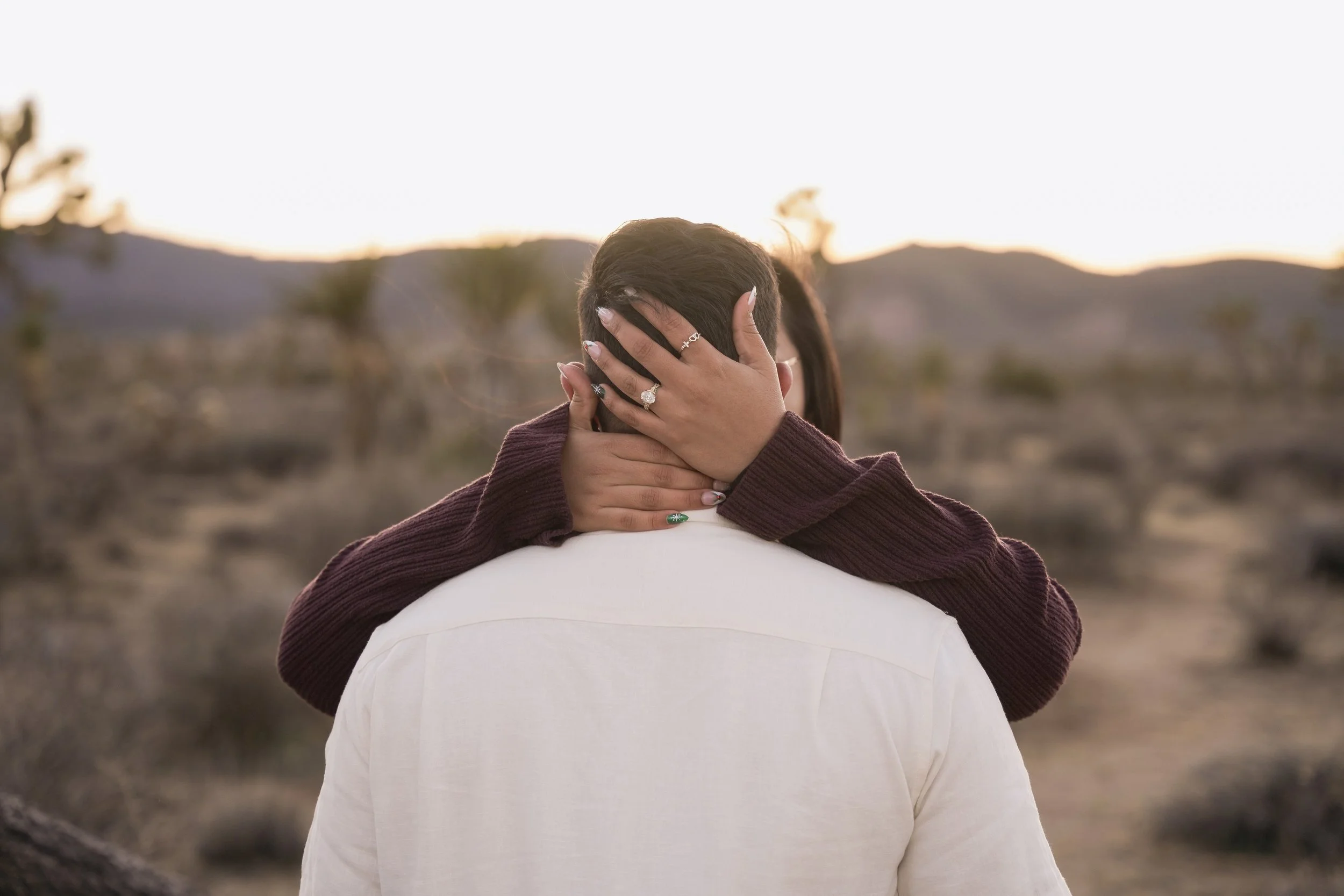 Fiancée hugging her future husband after a surprise proposal in Joshua Tree, framed by iconic Joshua trees at golden hour.