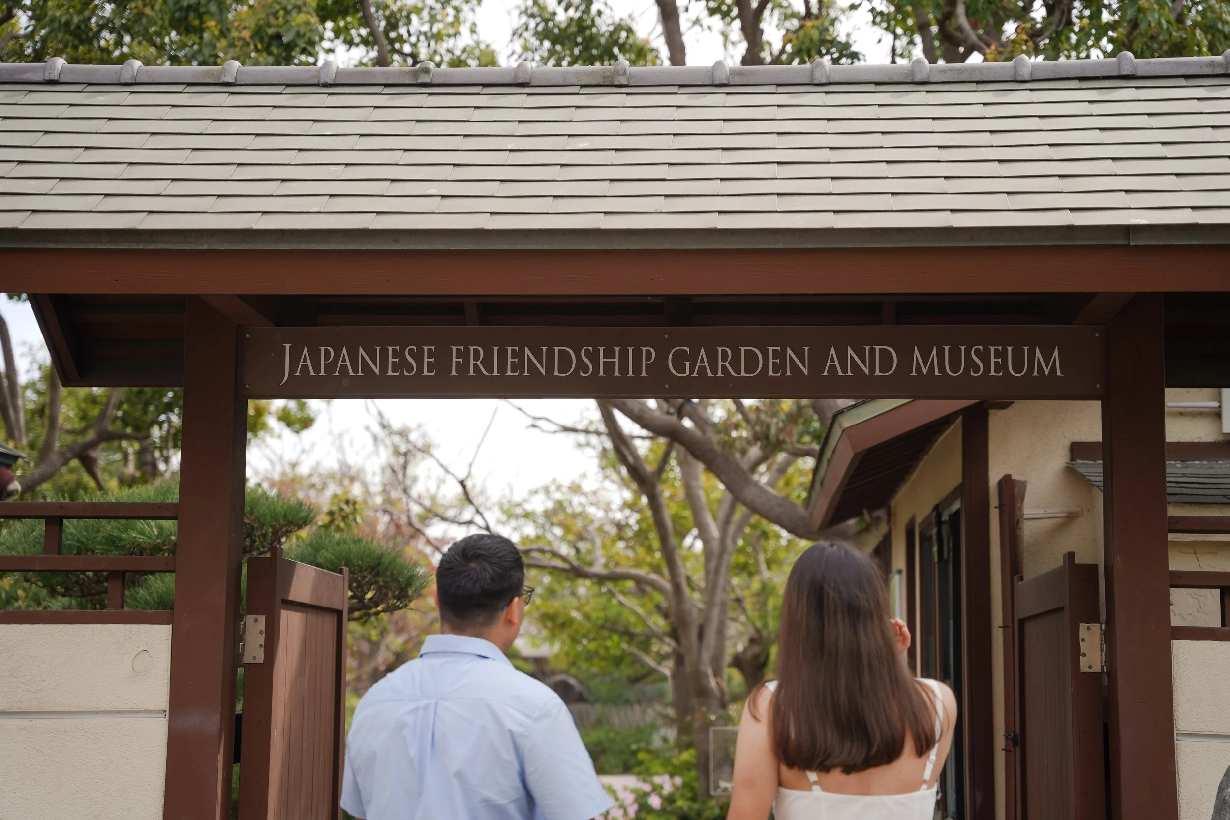 Newly engaged couple holding hands in front of the Japanese Friendship Garden in Balboa Park after their surprise proposal in San Diego