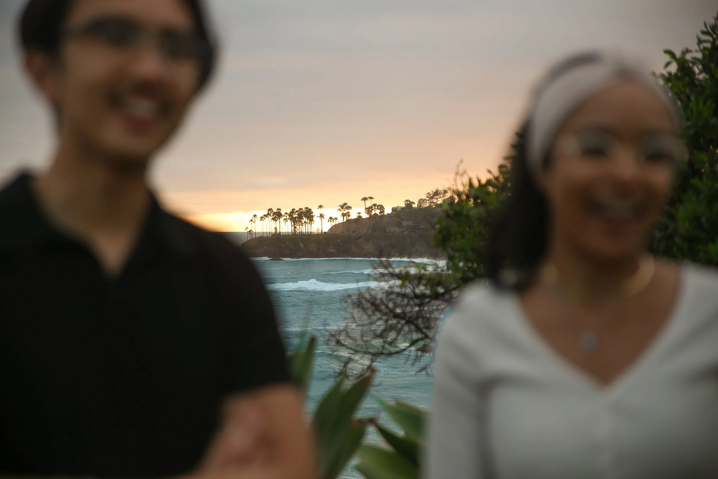 Recently engaged couple embracing during sunset after a surprise proposal at Heisler Park in Laguna Beach, California, overlooking the Pacific coastline during golden hour, photographed by a Laguna Beach proposal photographer.