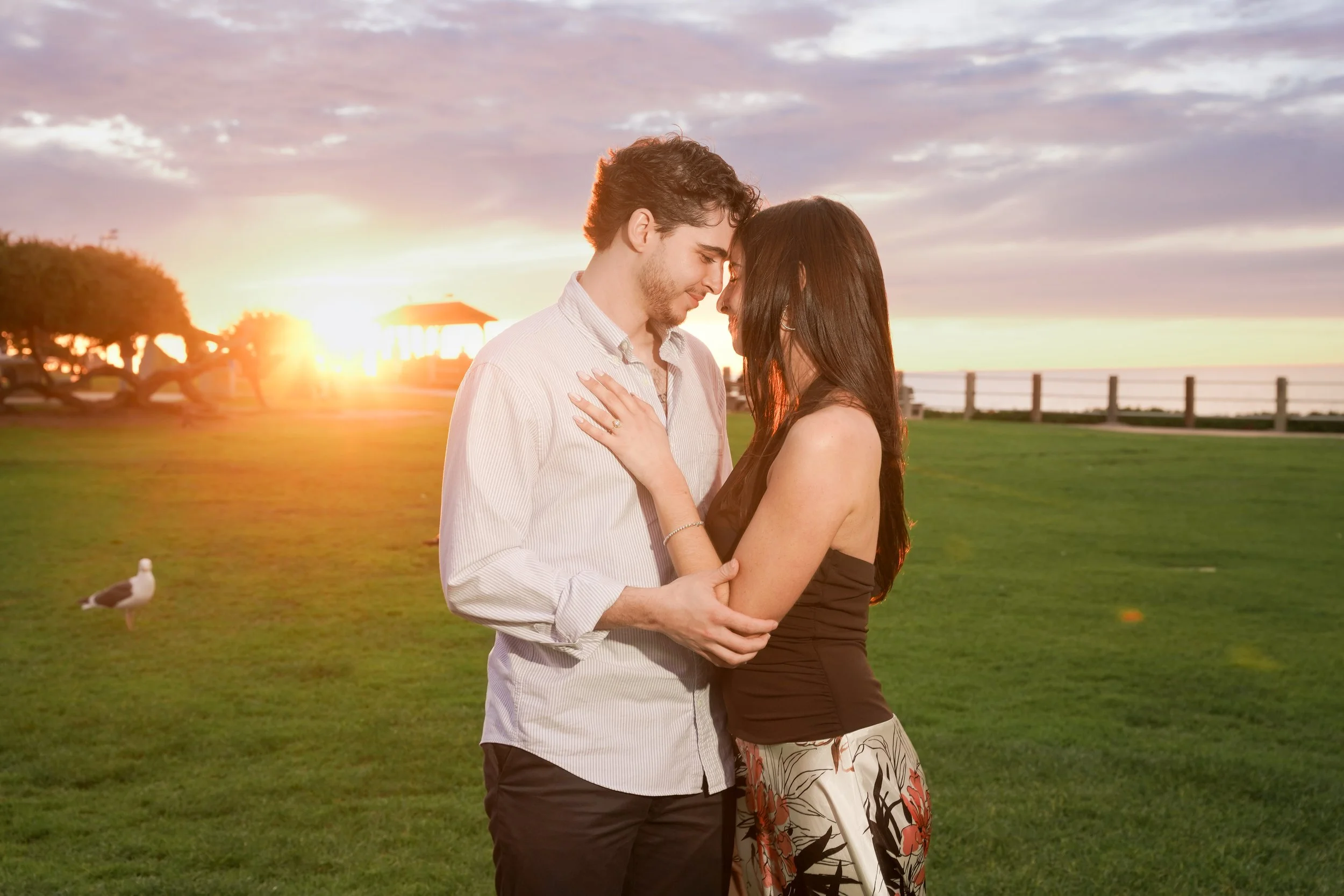 **Alt Text:** Sunset engagement photo at Scripps Park La Jolla Cove after a surprise proposal in golden hour light.