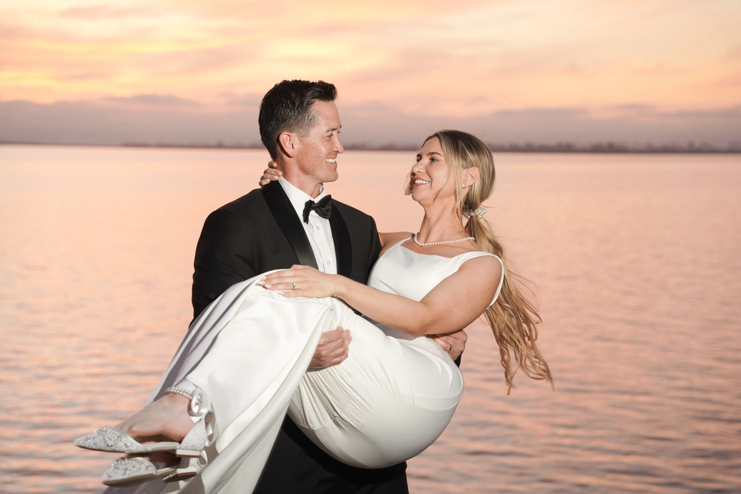 Newly married couple embracing at Marina Park in Chula Vista during golden hour, with the groom holding the bride after their courthouse wedding, captured in soft natural light.