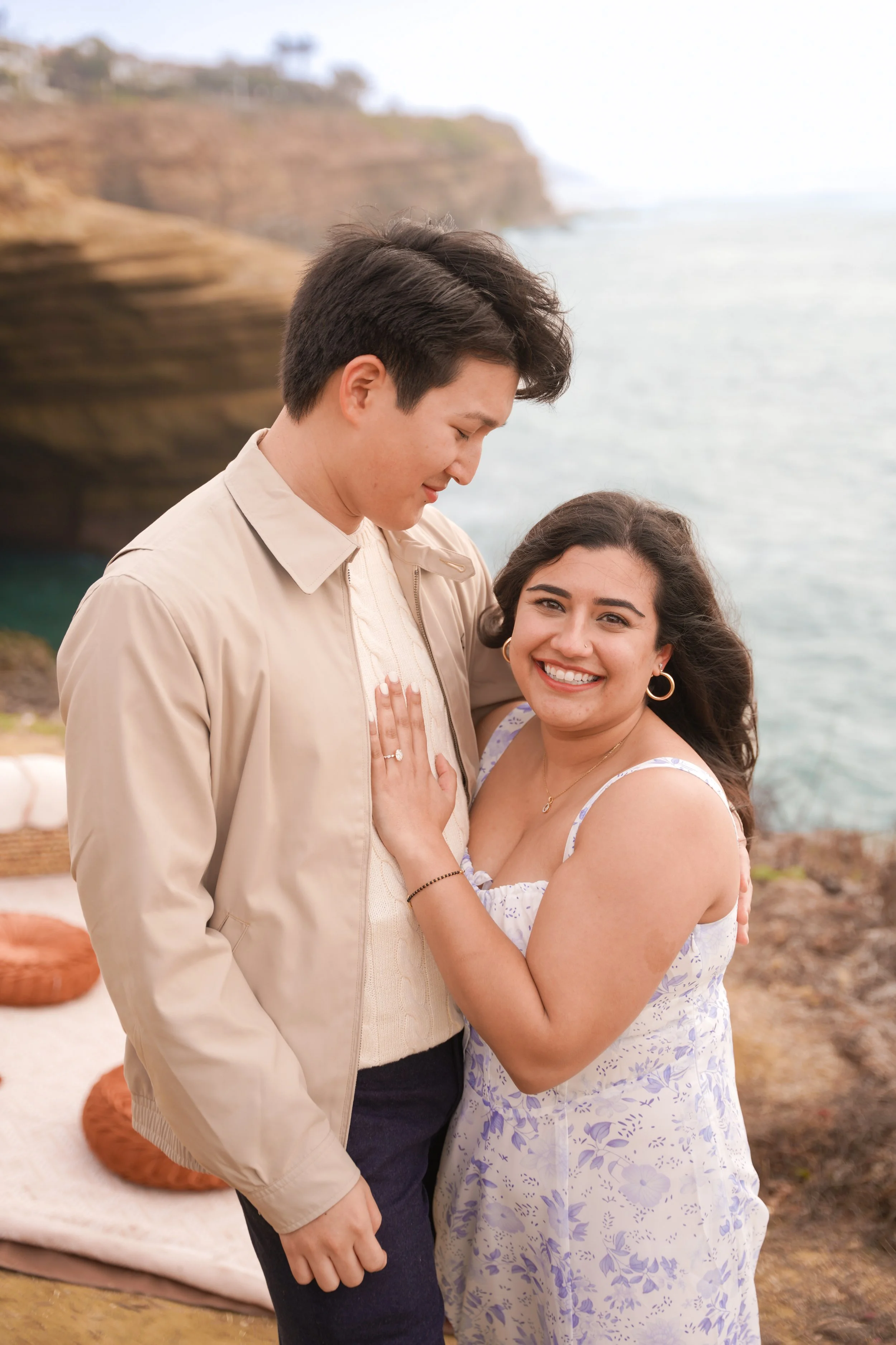 Surprise proposal photography at Sunset Cliffs featuring a boho picnic setup, documenting a romantic moment along the San Diego coastline.