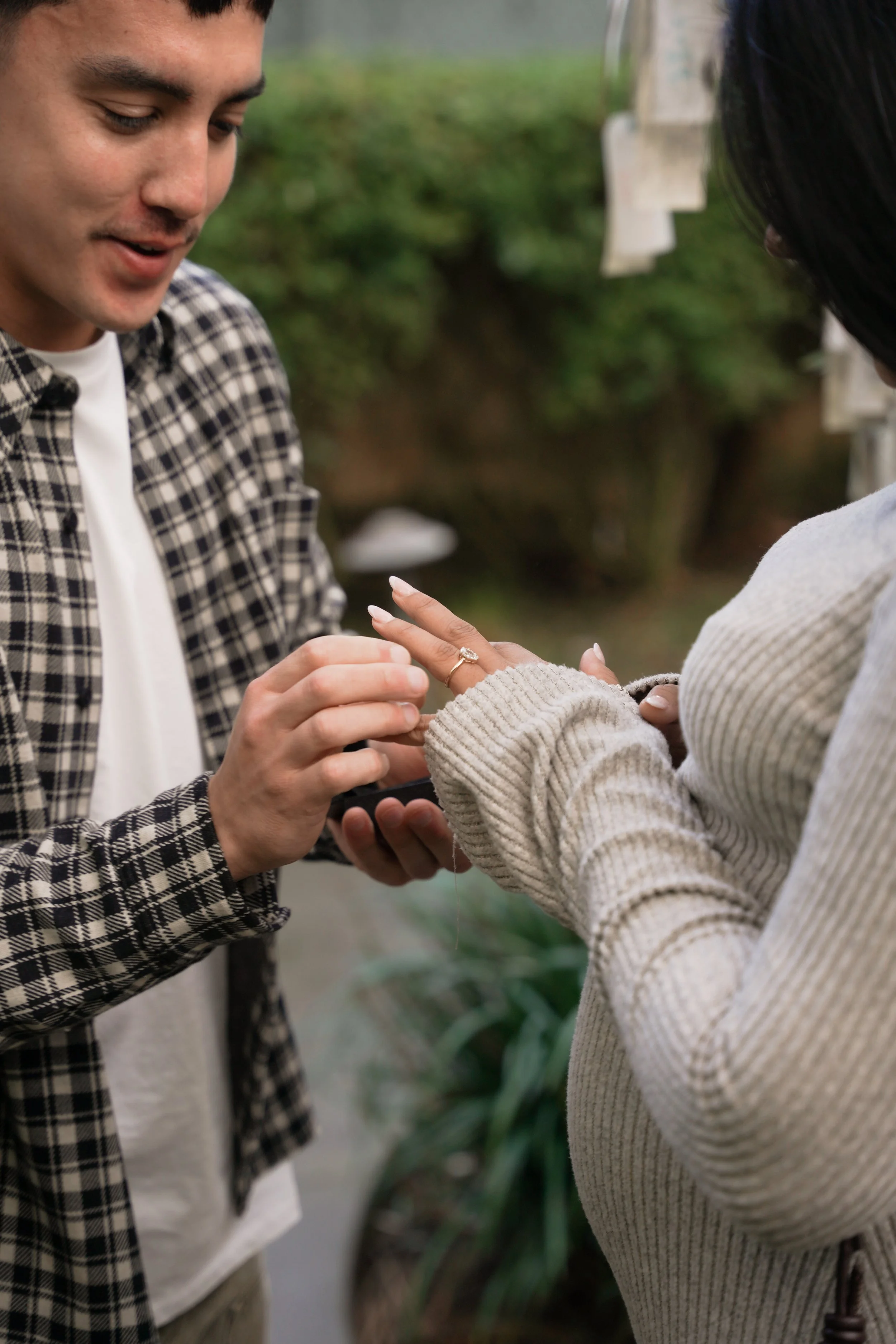 Emotional moment as she reacts to the surprise proposal under the Wishing Tree at Estancia La Jolla, with soft natural light framing the scene.