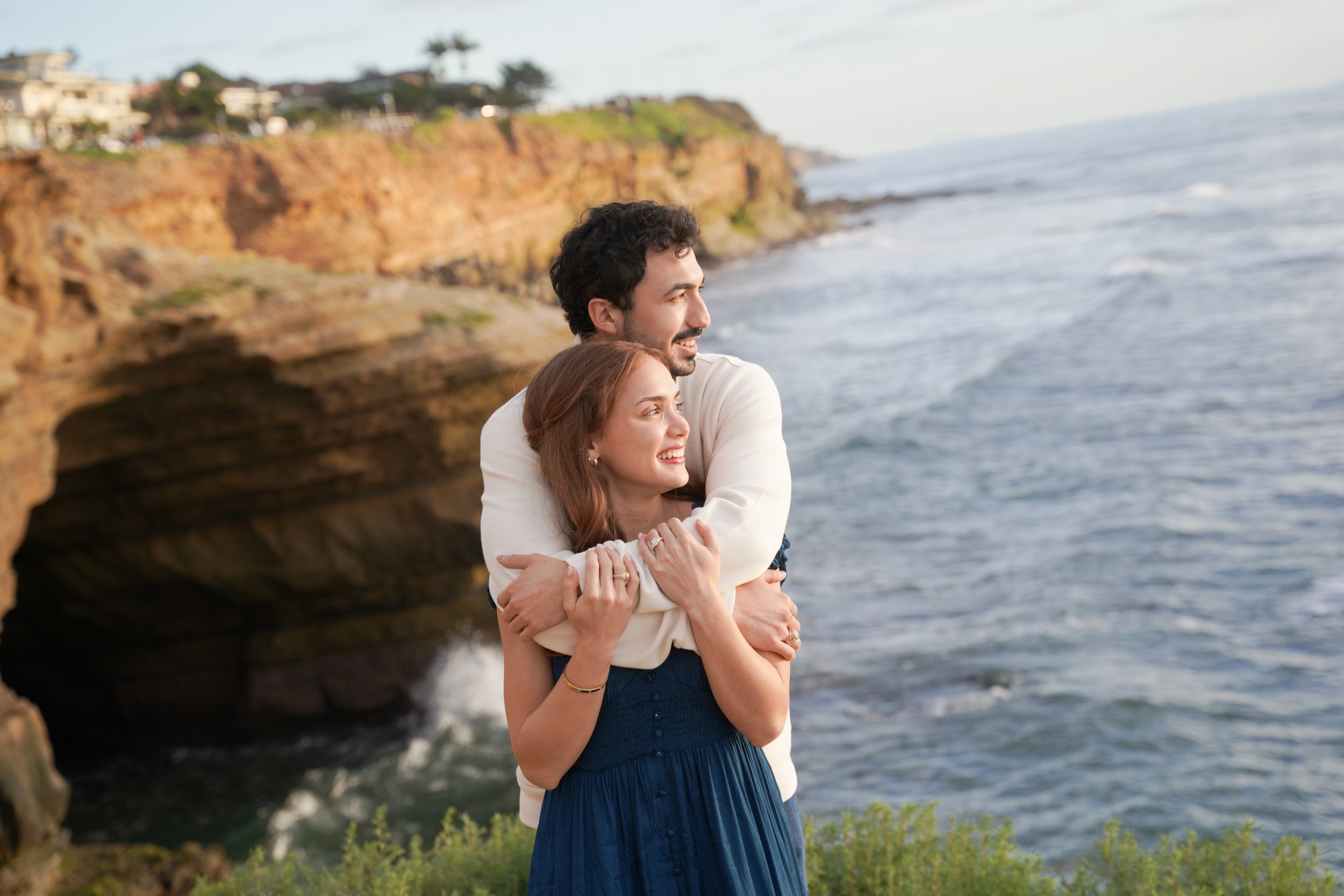 Couple embracing after a surprise proposal at Sunset Cliffs San Diego during golden hour with ocean views and sunset sky