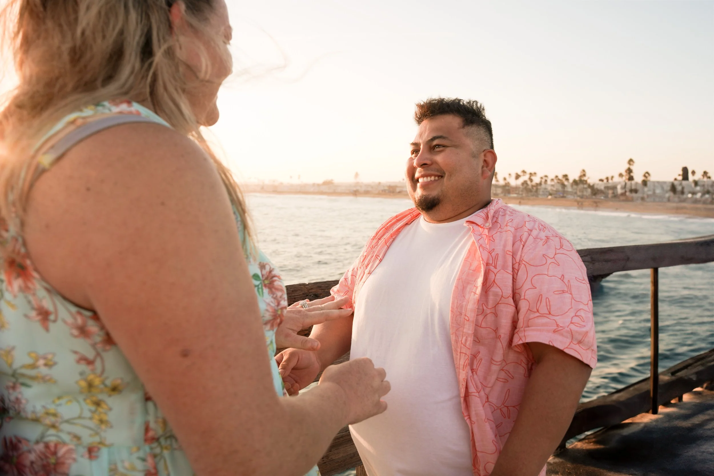 Orange County engagement photography of Miguel’s proposal at Balboa Pier, Jennifer smiles as Newport Beach sunset lights the moment.