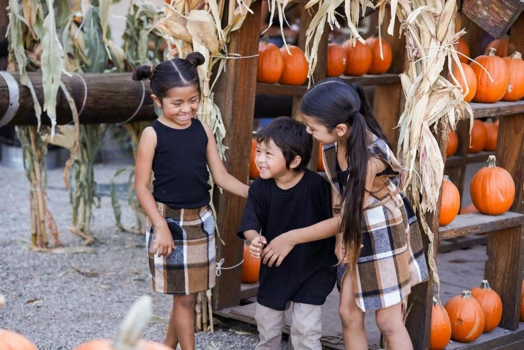 Lifestyle portraits capturing family bonding at a seasonal pumpkin patch.