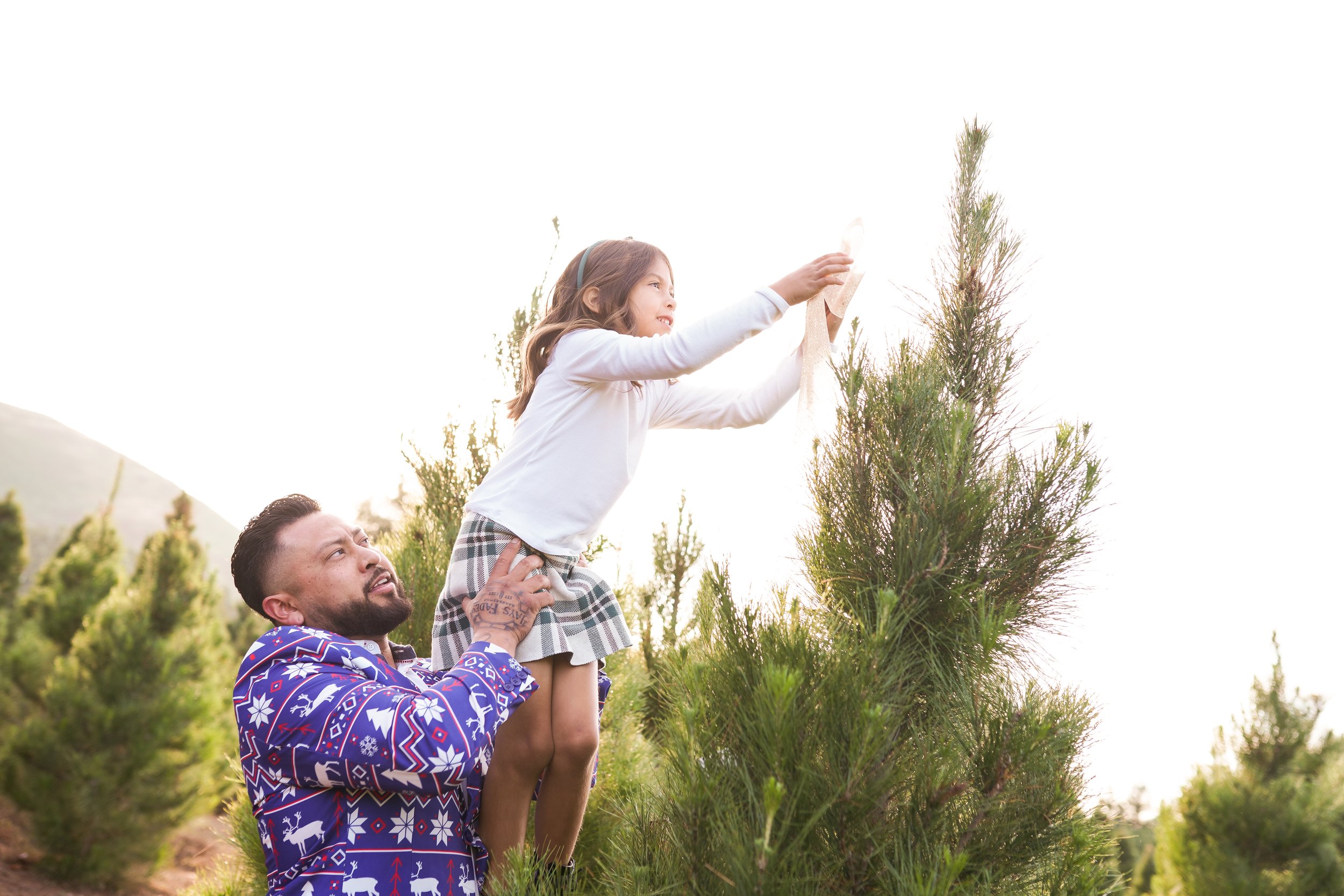 A cozy holiday session capturing a family's joy as they picked out their Christmas tree and placed the star on top. A beautiful moment of togetherness and new traditions—perfect for holiday family photography filled with warmth and cheer.