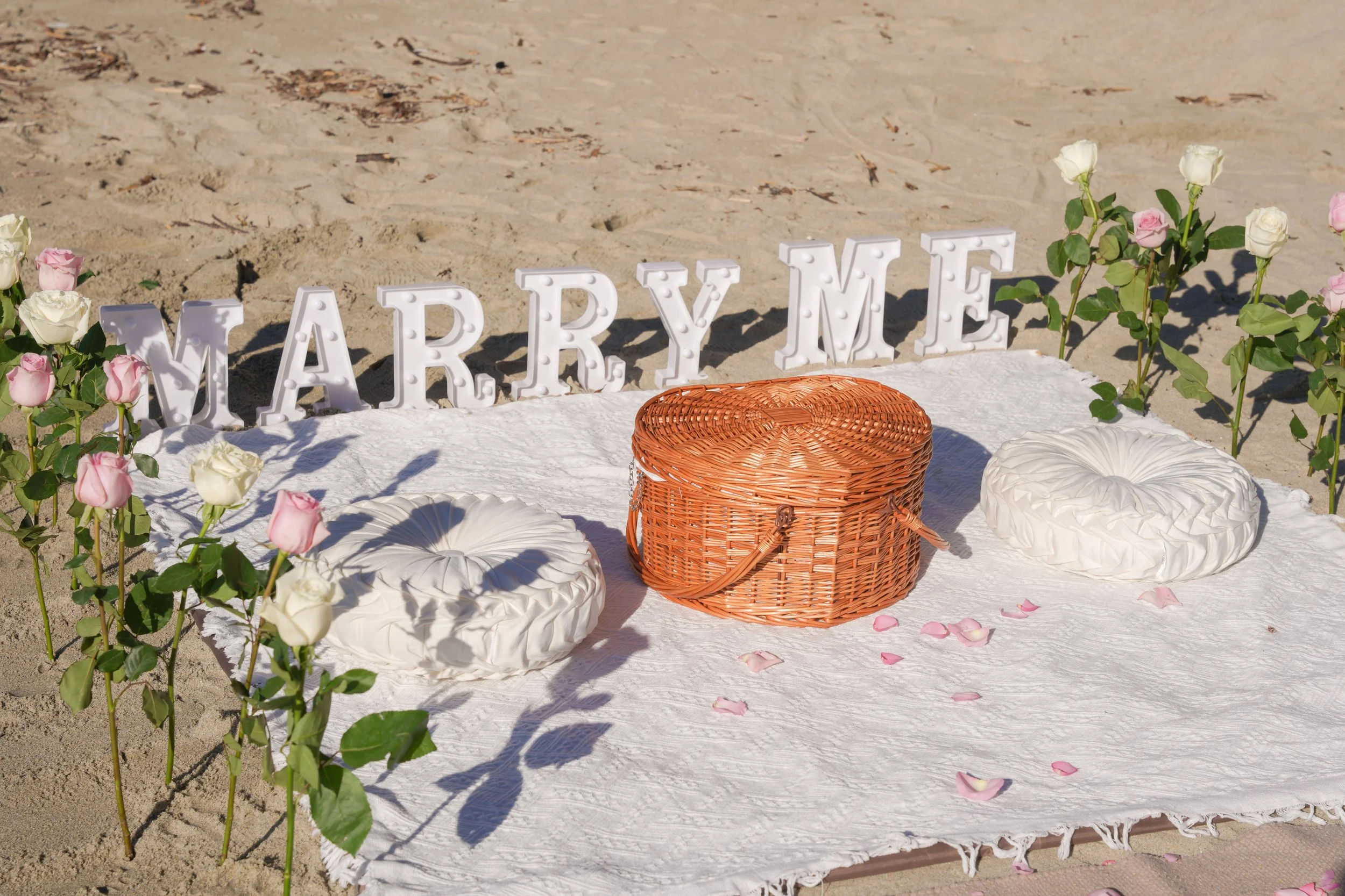 A minimal yet elevated Marry Me beach surprise proposal with roses, intentional décor, and professional photography focused on emotion and connection.