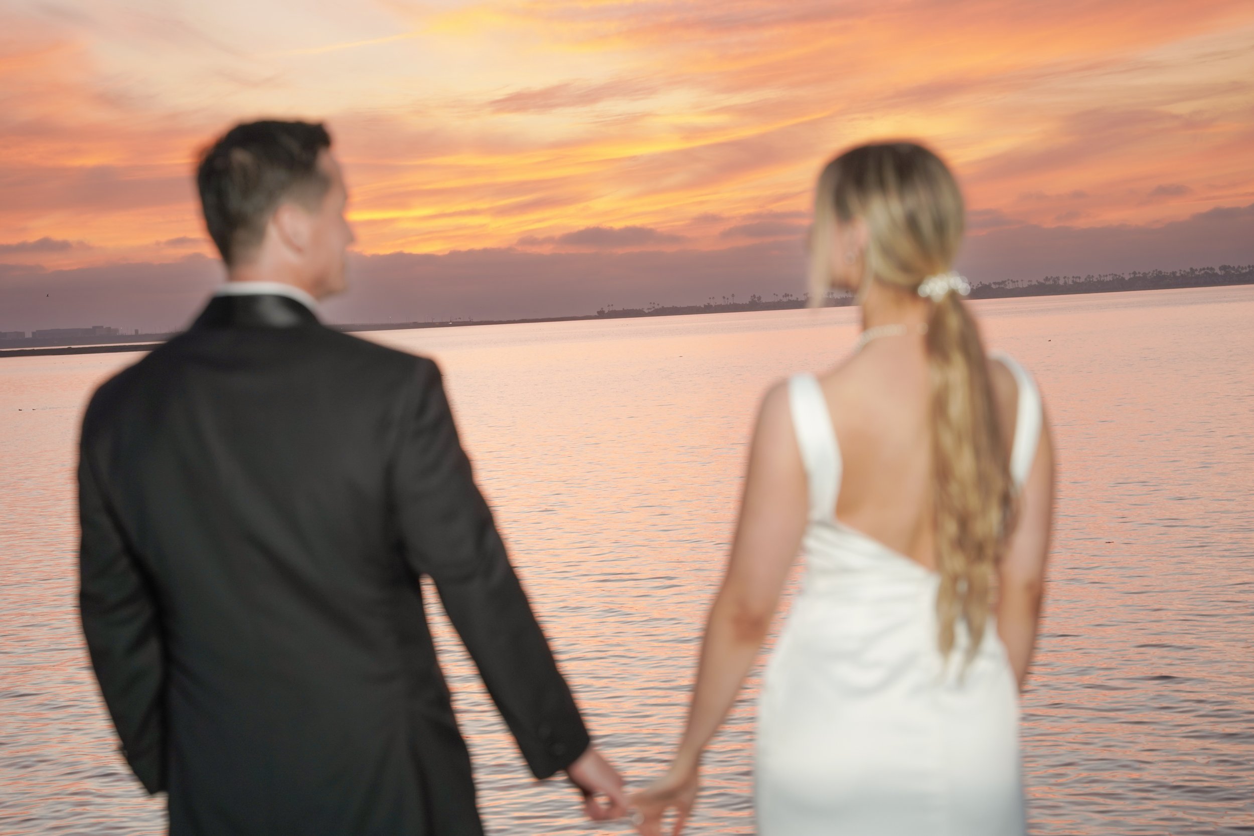 Couple watching sunset at San Diego marina after wedding ceremony, captured with natural light, waterfront views, and romantic newlywed portrait photography