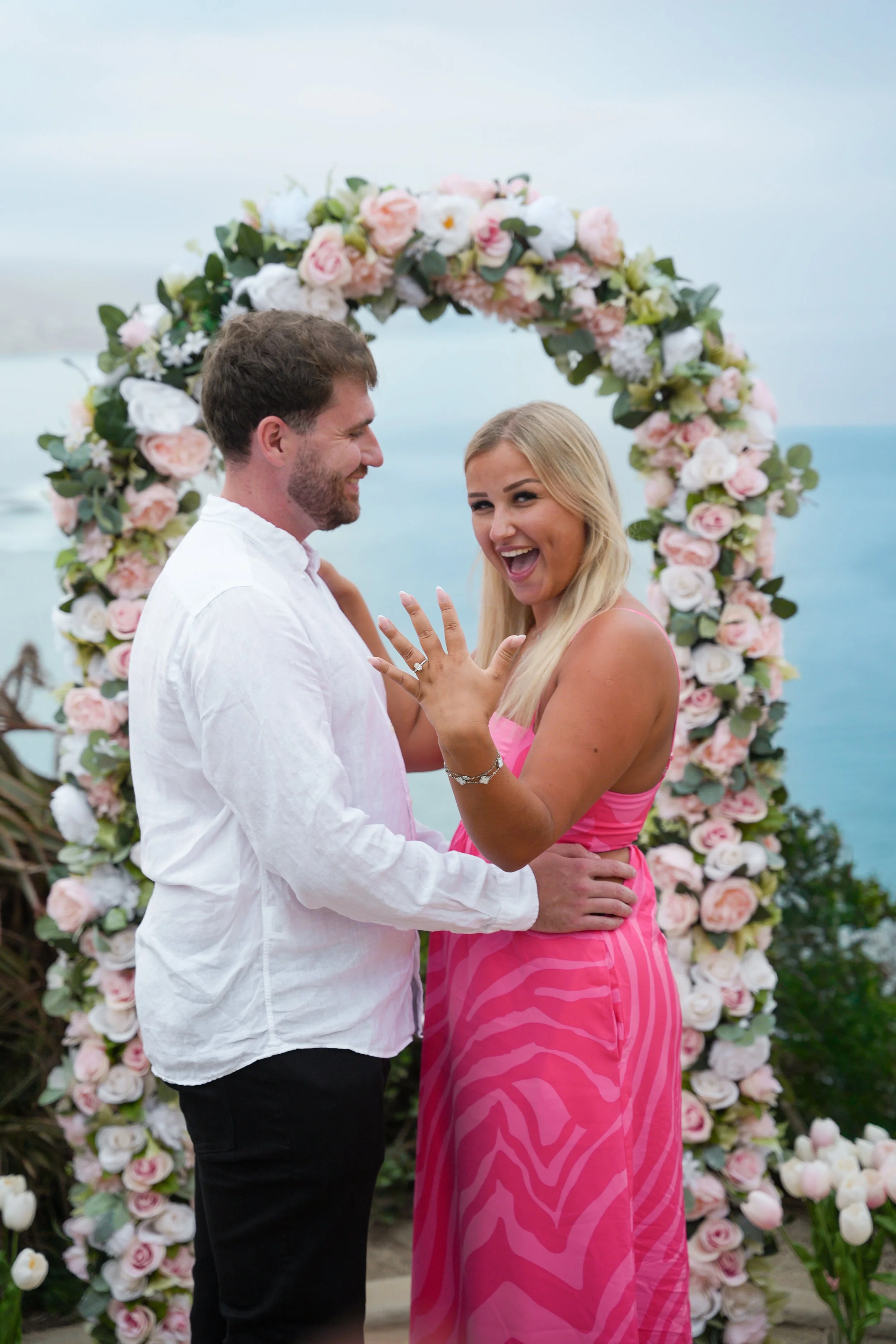 Oceanfront marriage proposal in Laguna Beach, California, featuring our Signature Yes floral arch.