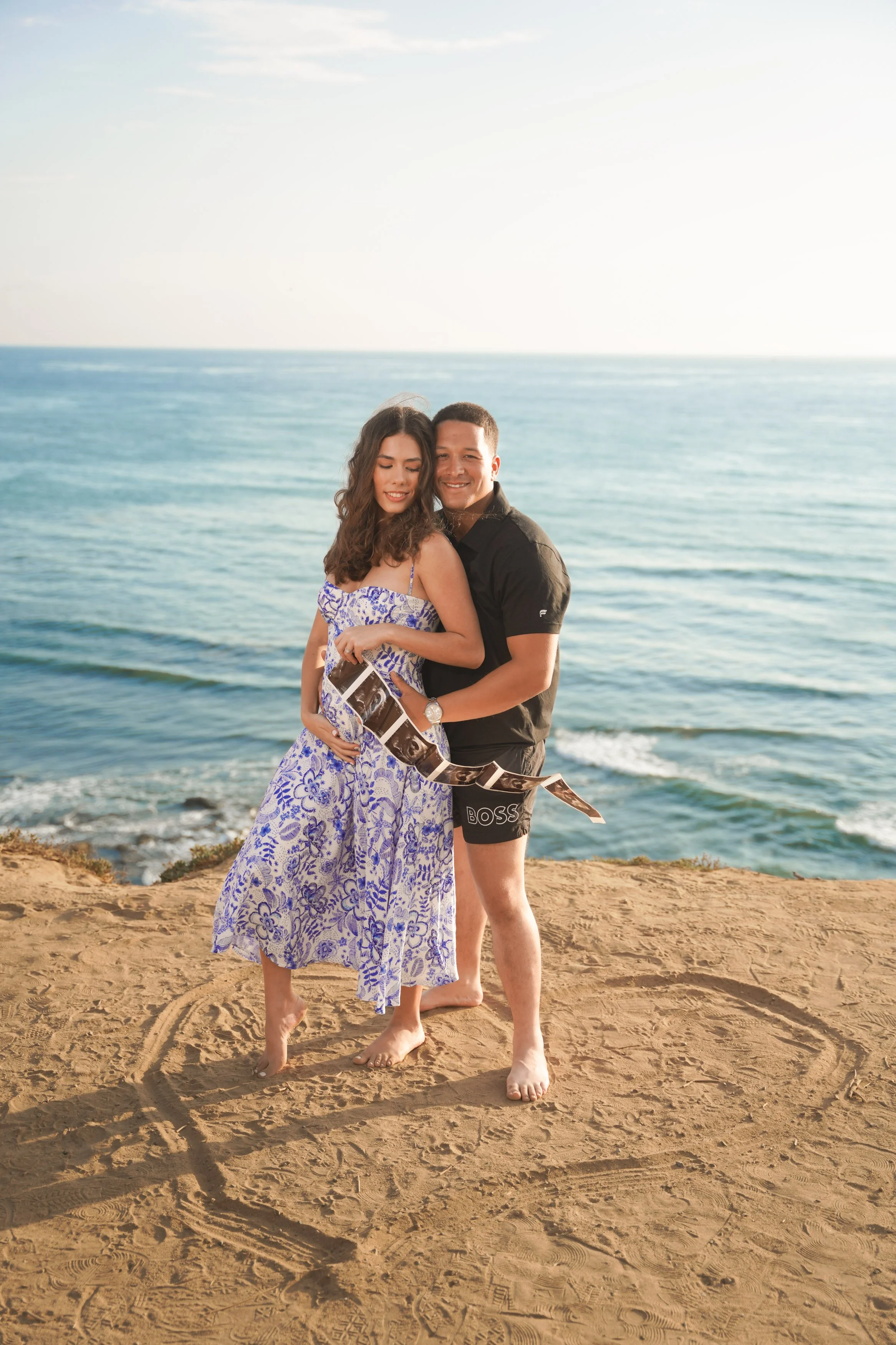 San Diego baby reveal photoshoot at Sunset Cliffs during golden hour with glowing skies, cinematic ocean landscapes, and timeless natural light, capture your unforgettable announcement session today.