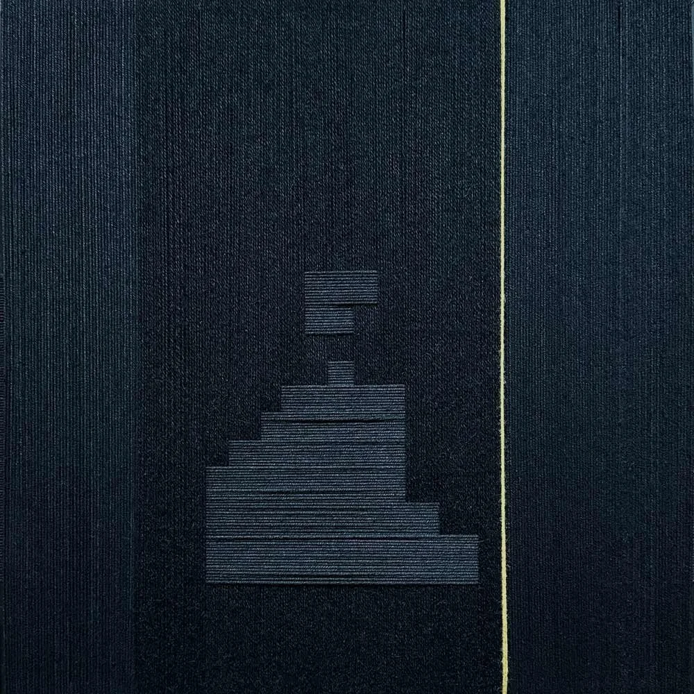 Black wool and bamboo threads wrap around a frame to create a stepping pattern in the center of mostly vertical wrap. A single gold thread runs vertically.