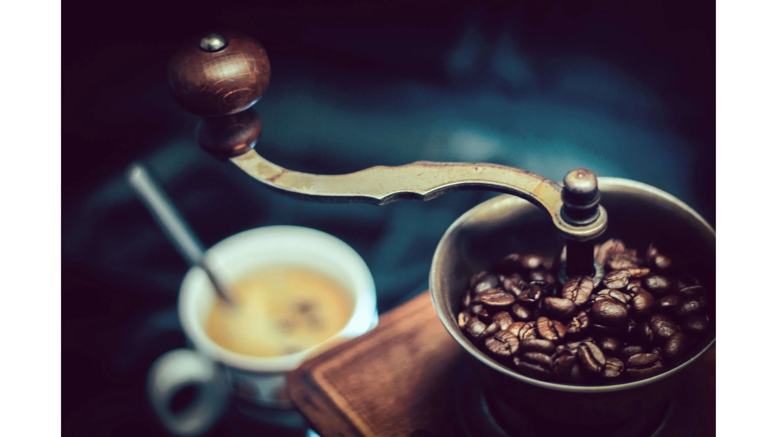 Photo of hand-cranked coffee grinder with a cup of coffee mold-free.