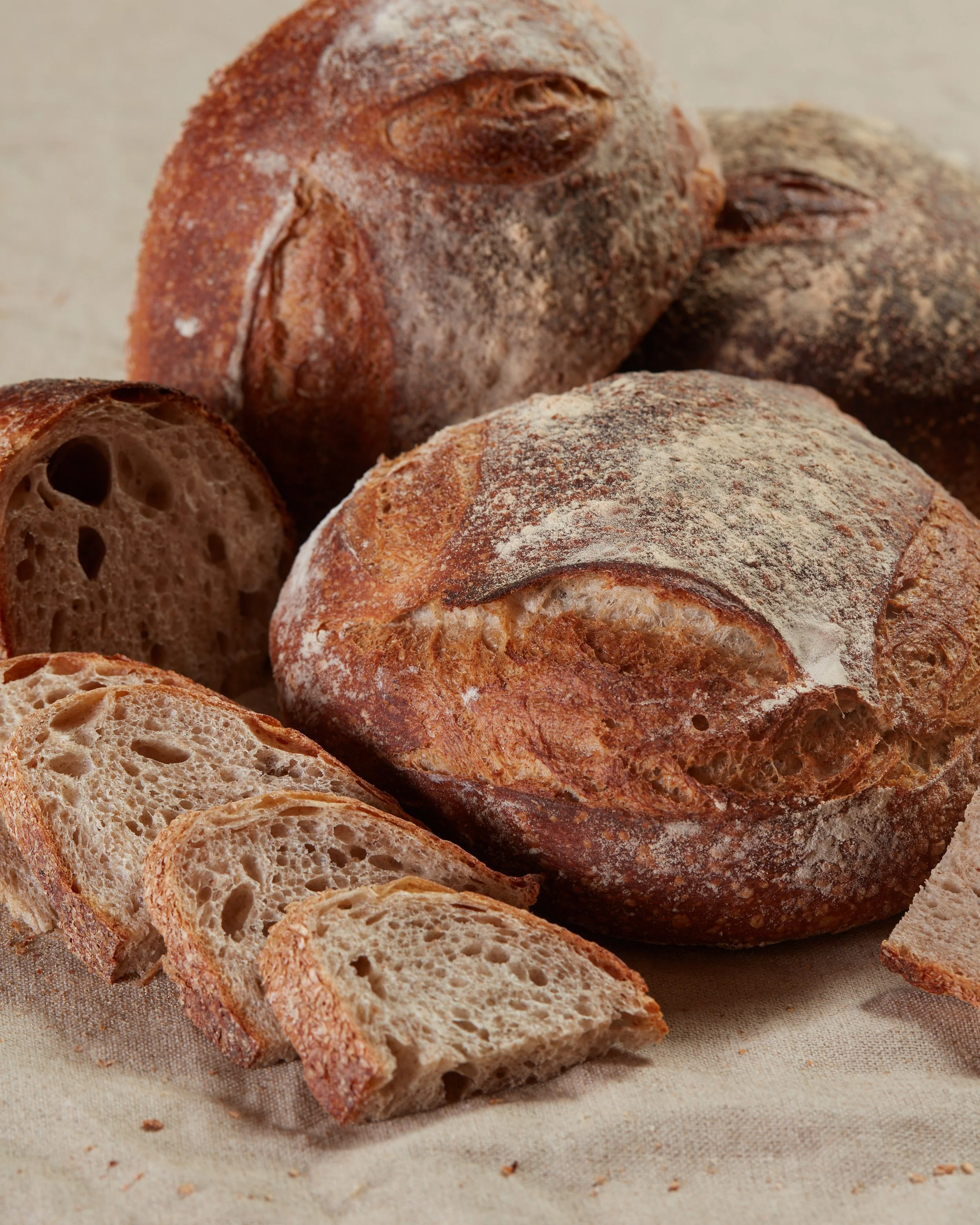 Crusty country loaf arranged in slices and loaves on a baking cloth.