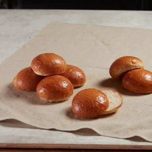Just baked hamburger buns stacked and sliced on a baking cloth.