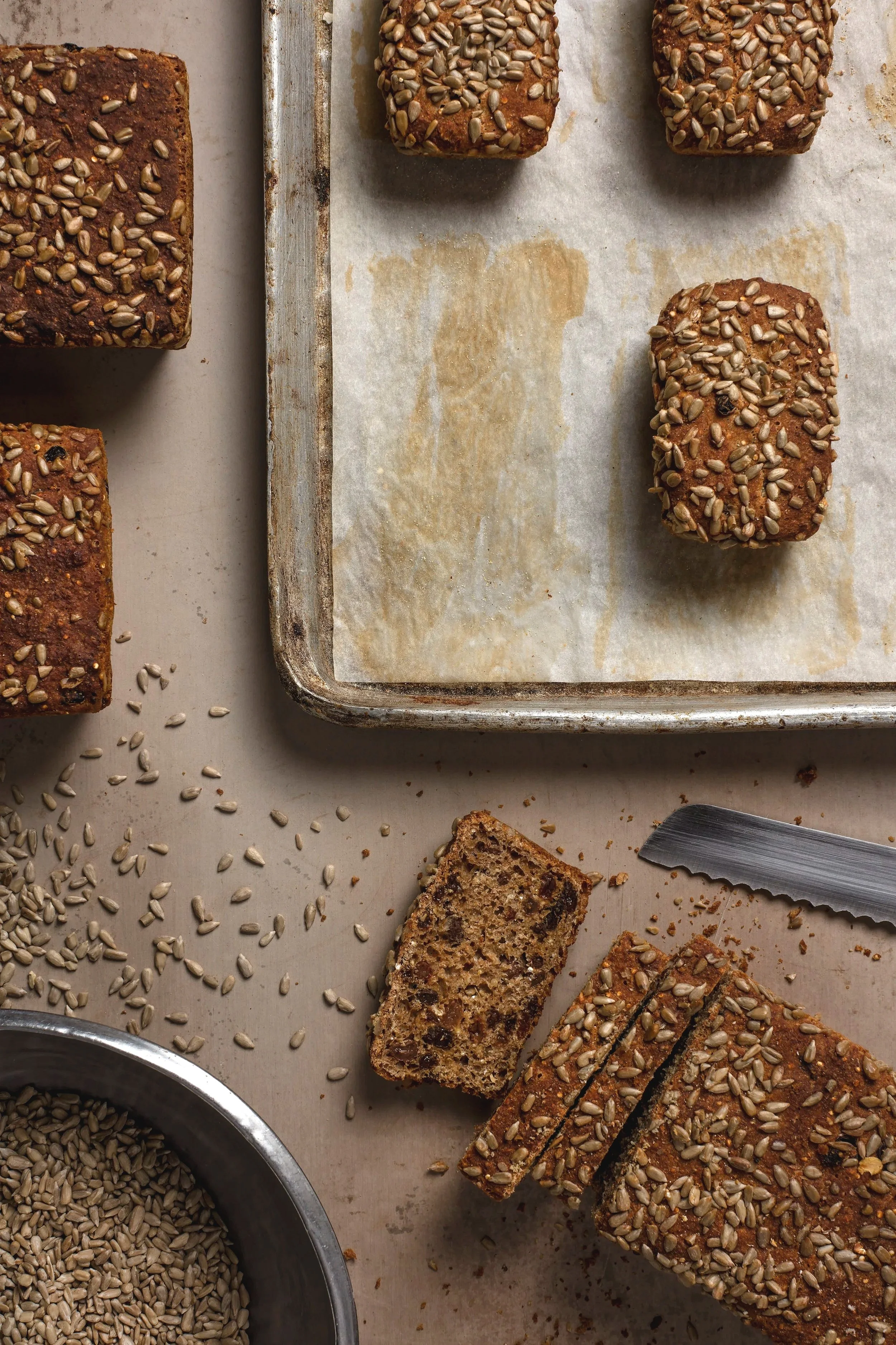 Sliced spelt bread on a round cutting board, with spreading peanut butter lathered on the top piece. 
