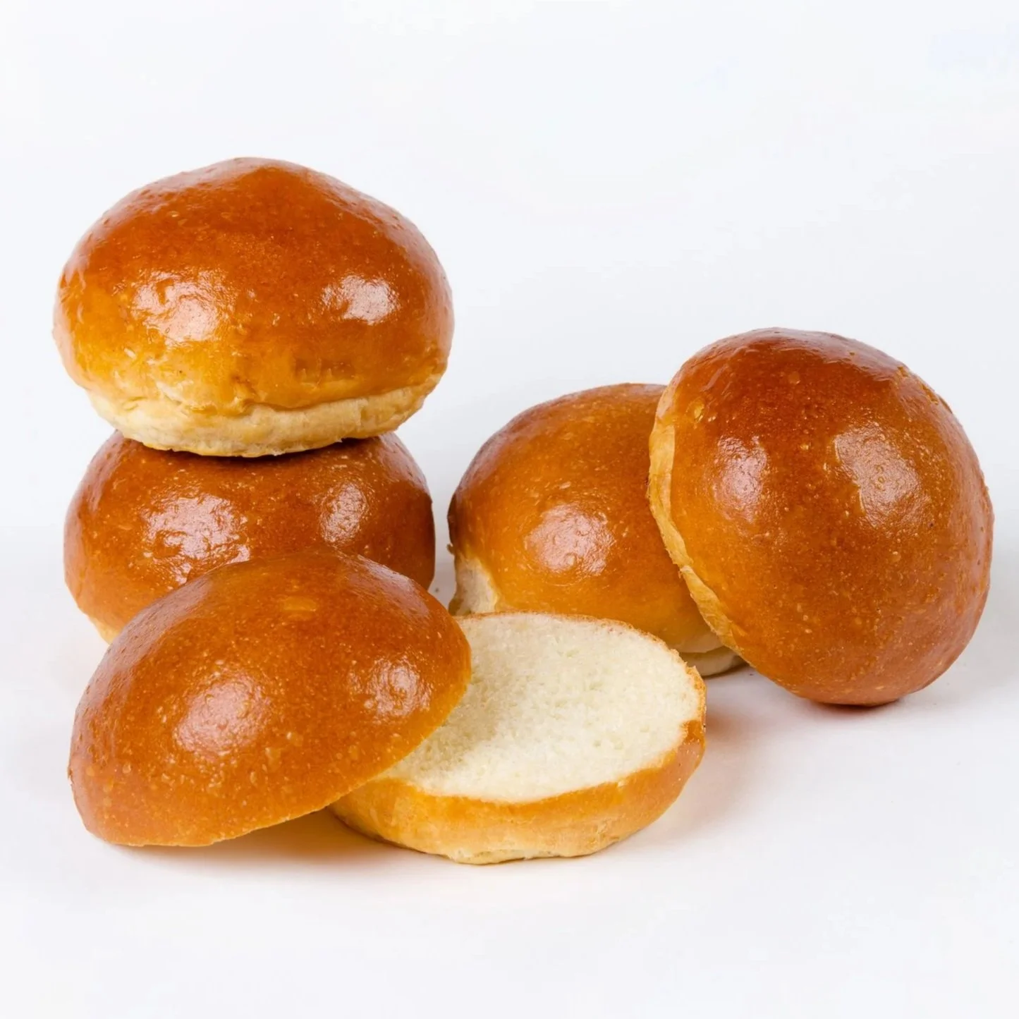Just baked hamburger buns stacked and sliced on a baking cloth. 