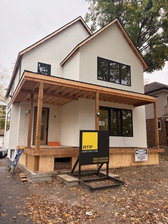 New two-story house under construction with a wooden porch and a sign that reads 'RTP Construction' in front.