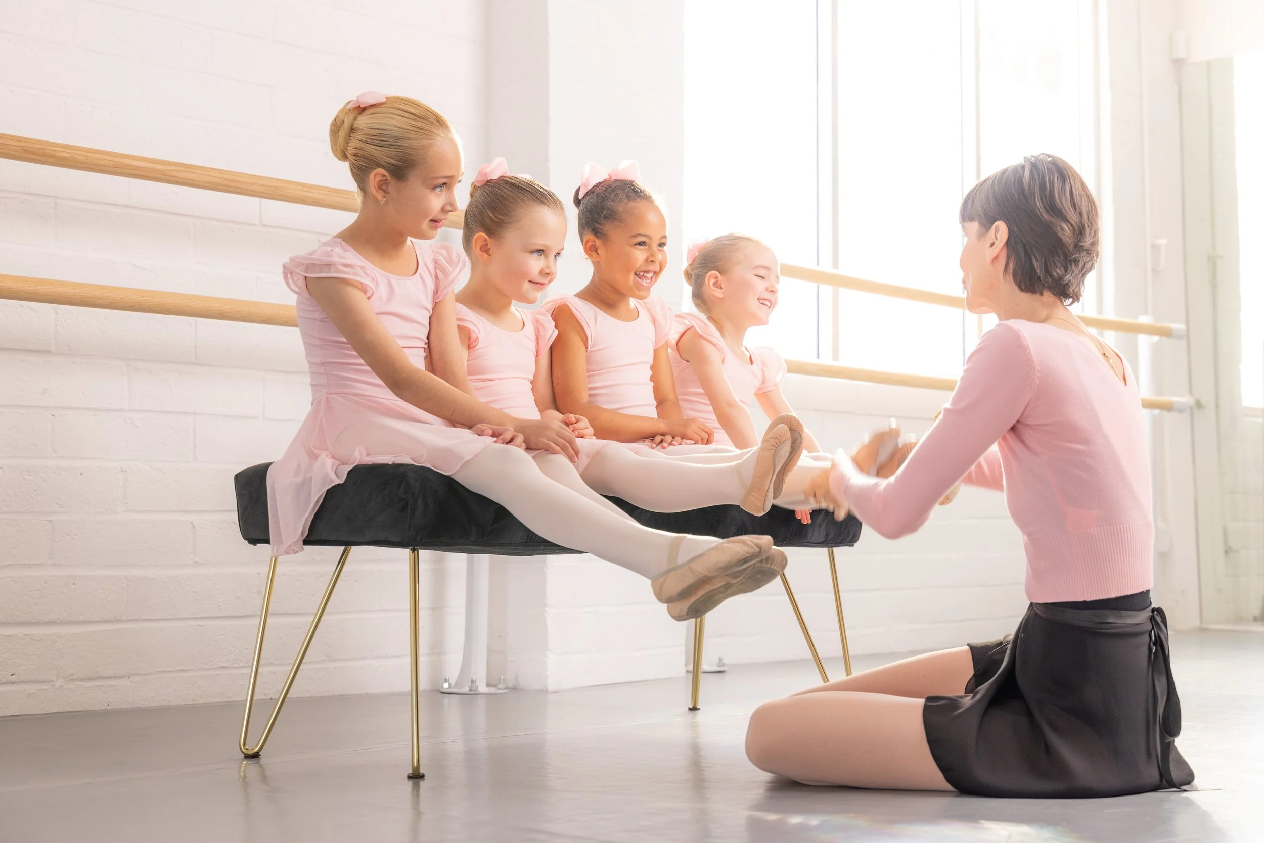 Miss Geraldine helping young students with their ballet shoes