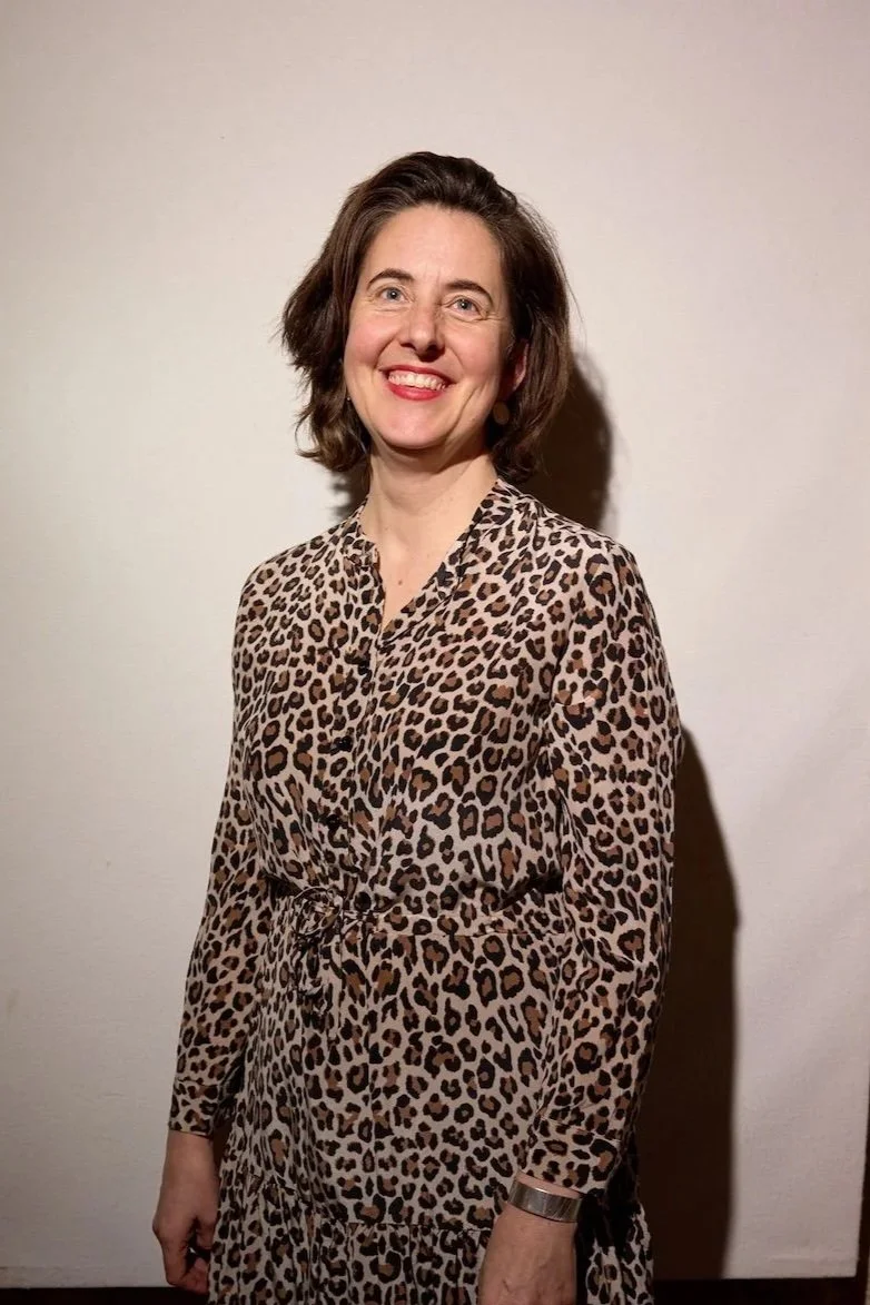 An image of a woman smiling in a cheetah print dress