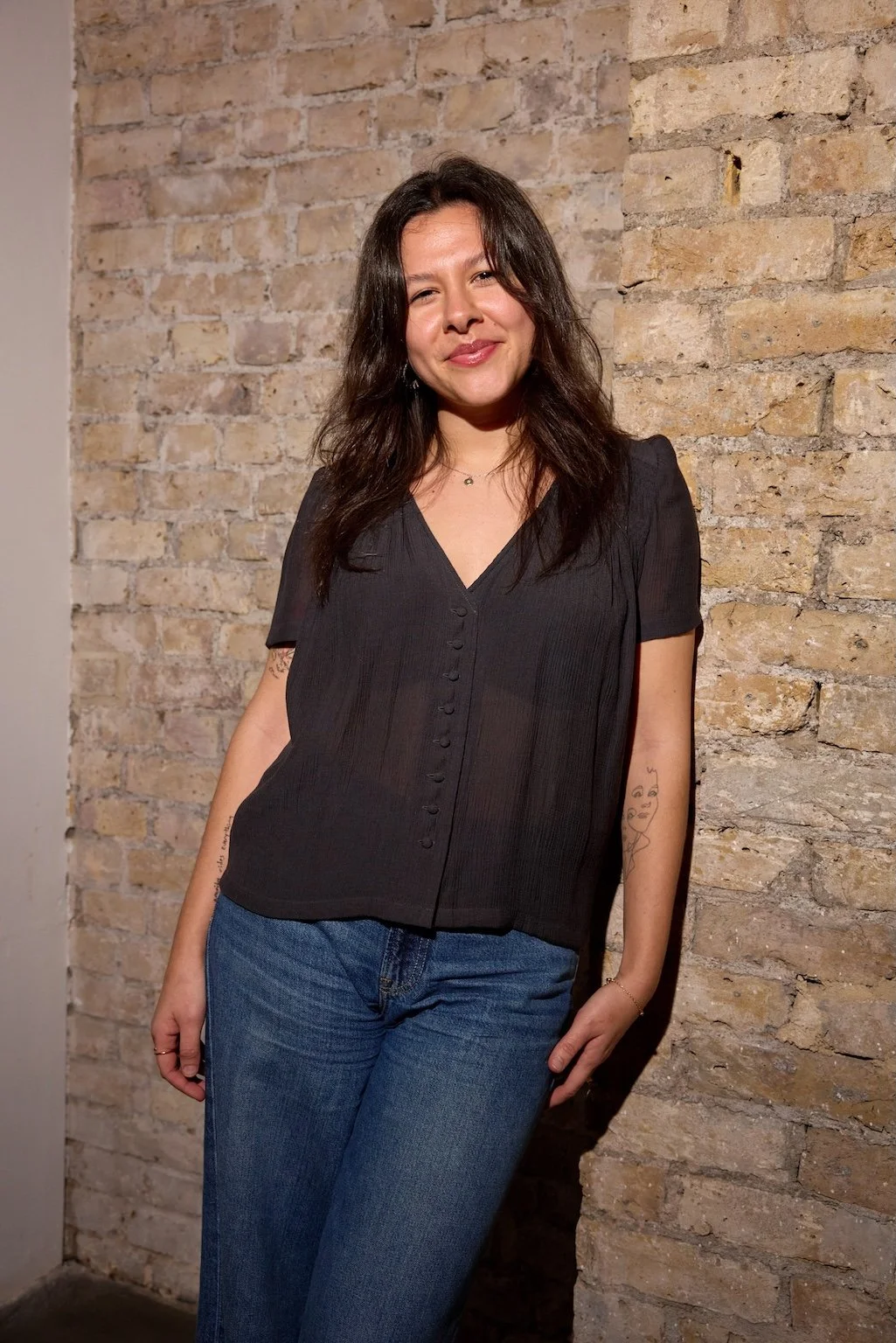 Woman smiling in front of a brick wall
