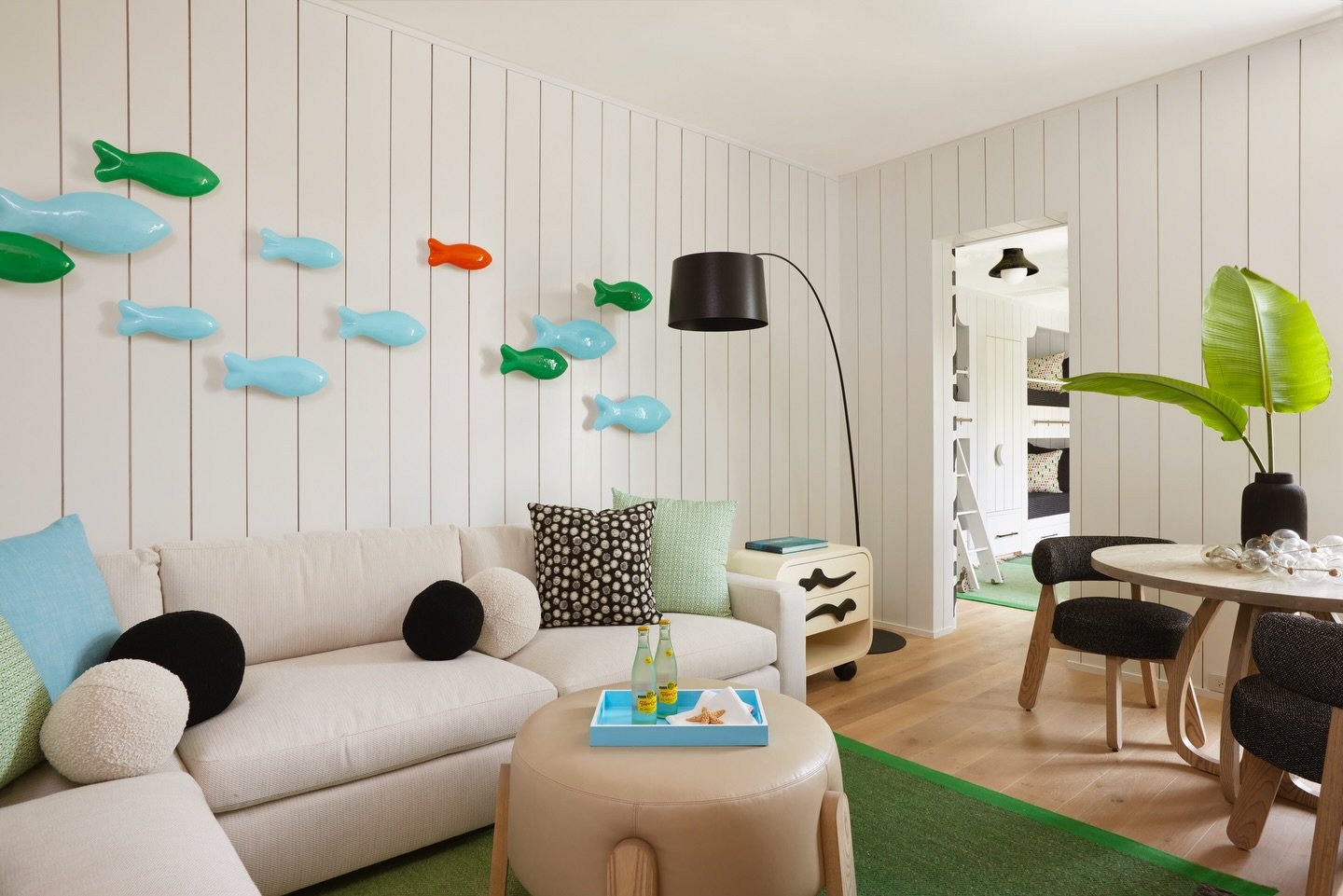 Weekend ready! Just off the bunk room, this playful lounge invites guests to unwind with art, color, and a touch of whimsy. Handblown glass fish add personality to the walls, while sculptural furniture pieces and soft sand tones keep it feeling eleva